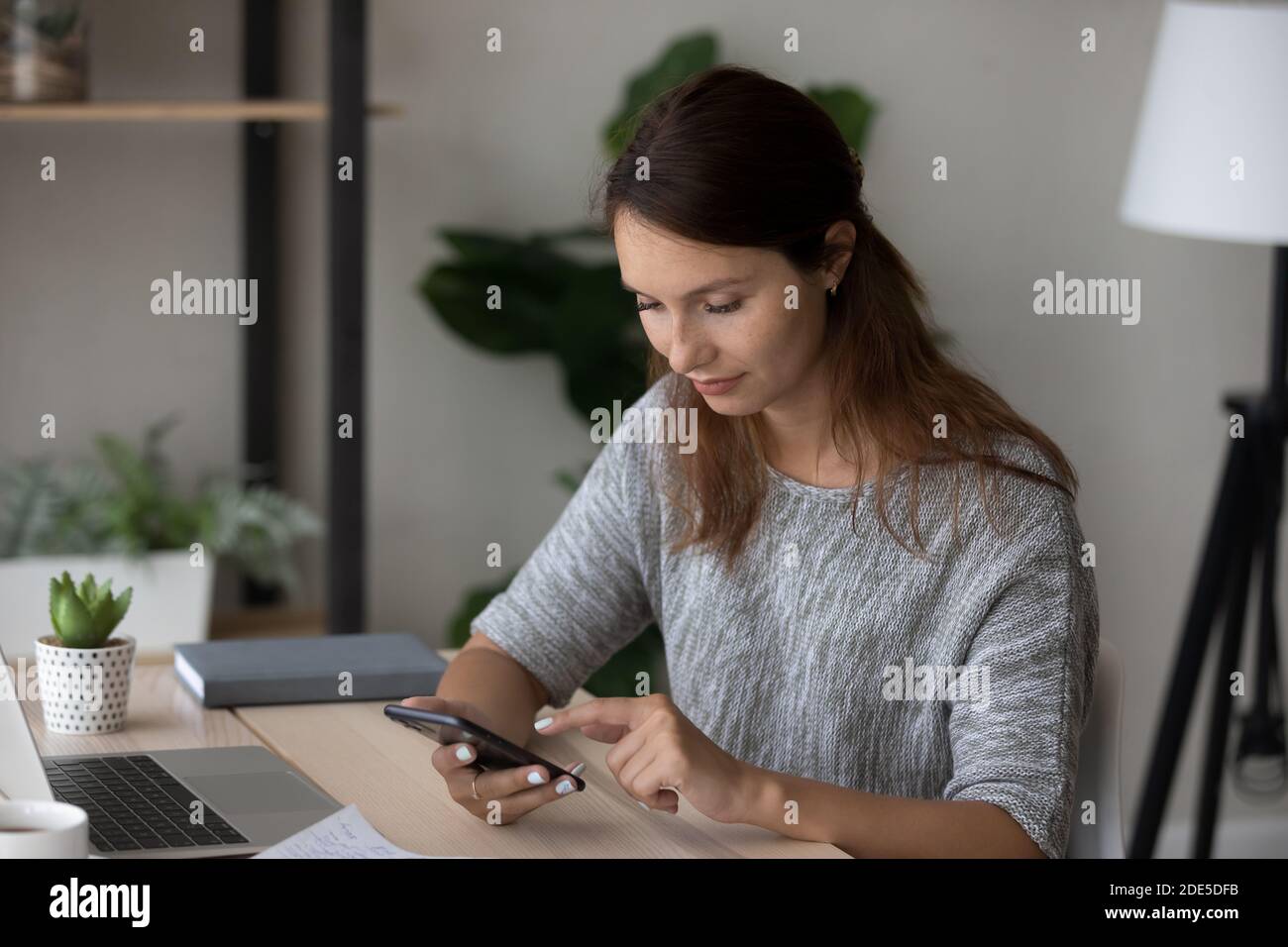 Angenehme glückliche tausendjährige rothaarige Frau mit mobilen Anwendungen. Stockfoto