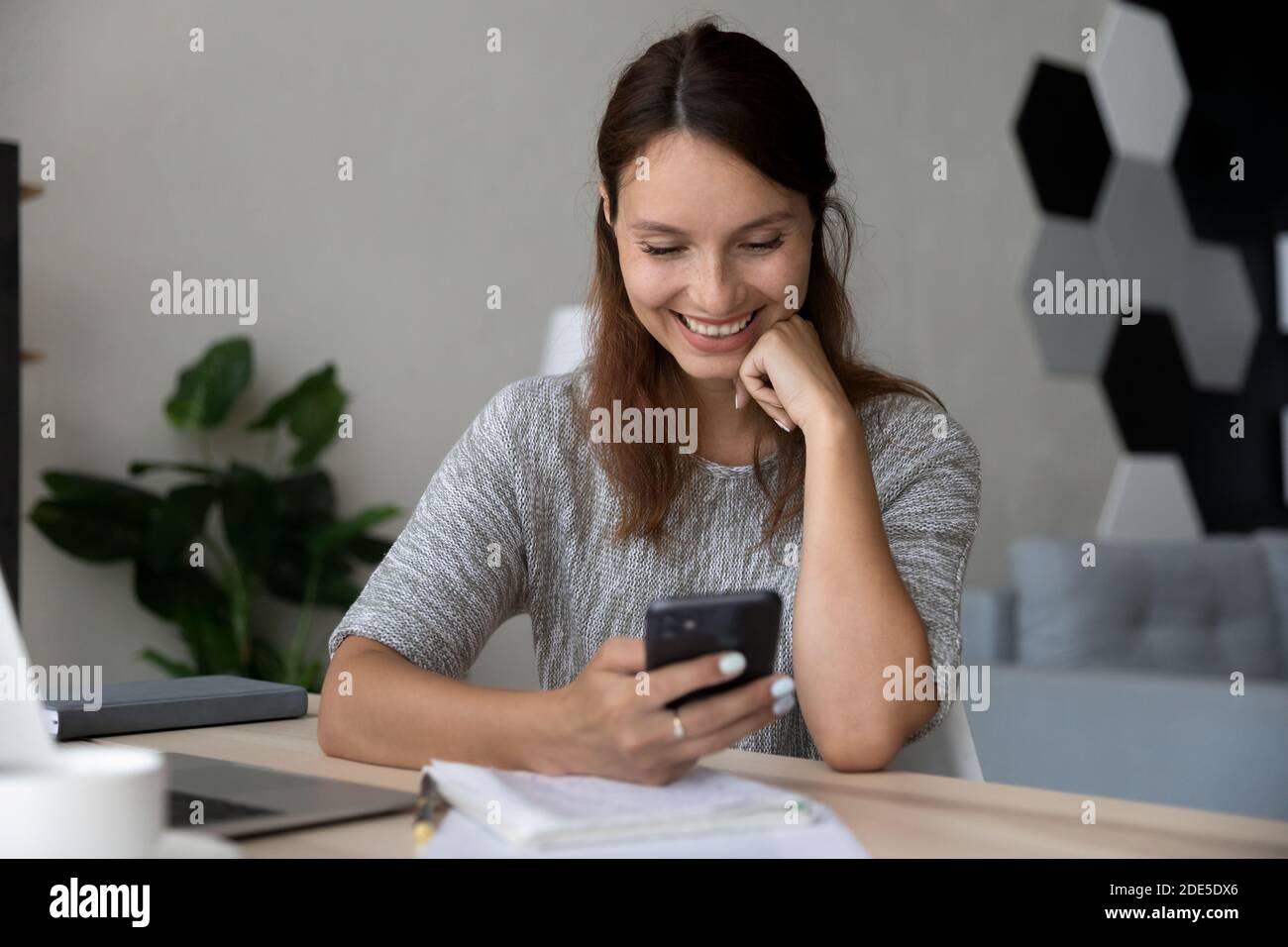 Abgelenkt von Studie lächelnde Millennial Frau in sozialen Netzwerken kommunizieren. Stockfoto