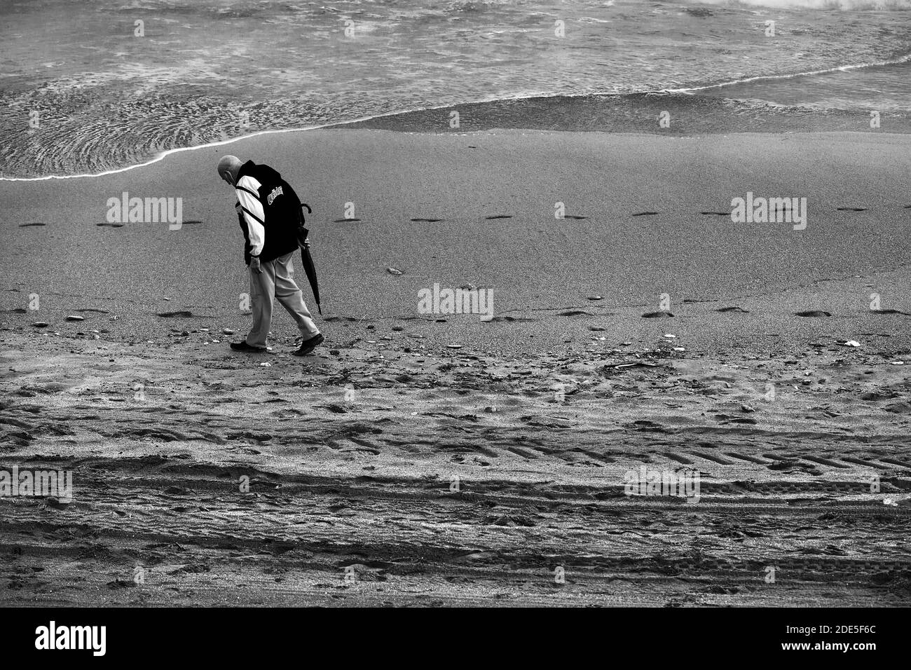 Alter Mann, der am Strand entlang schlendert, Barcelona. Stockfoto