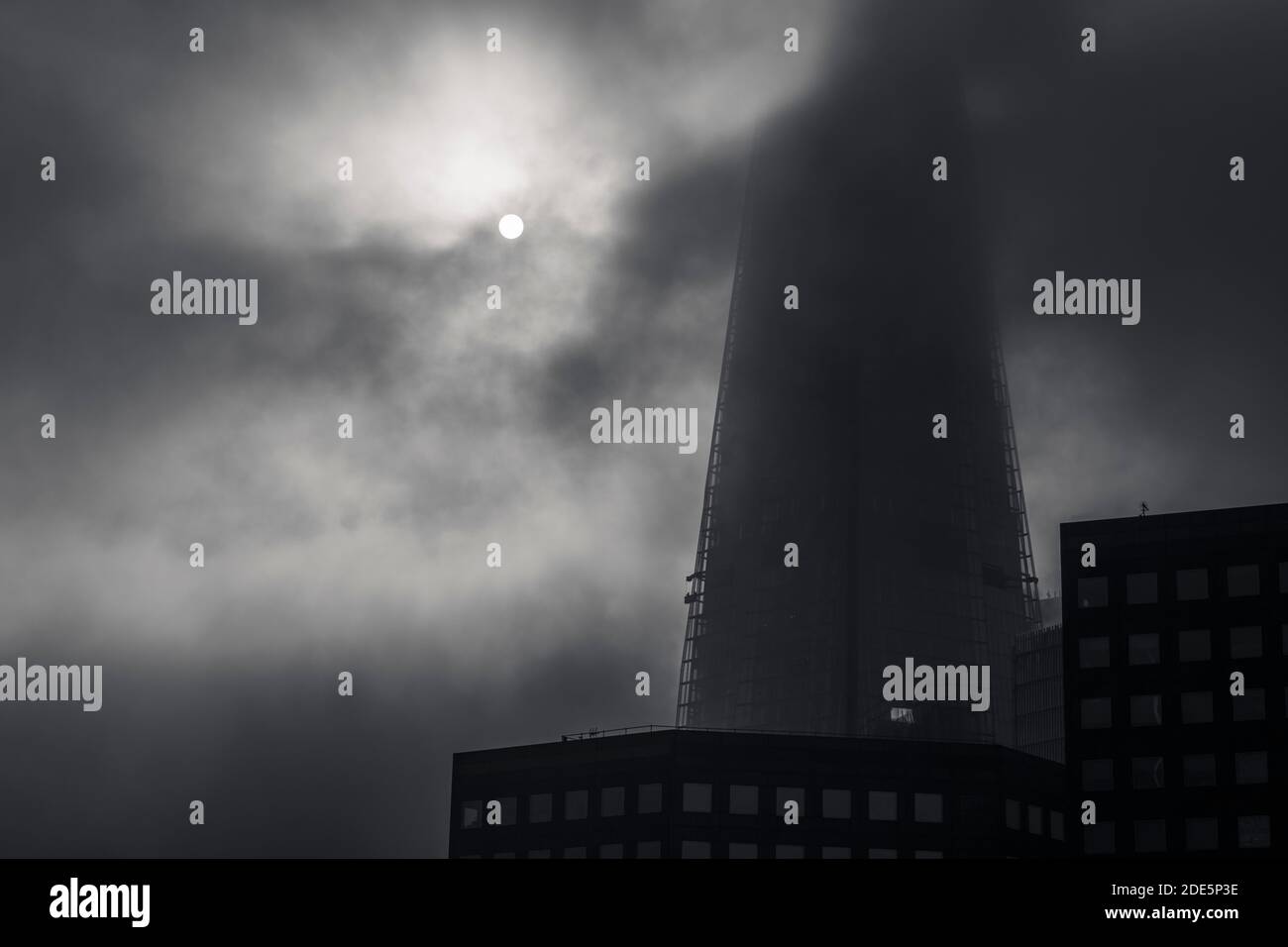 Schwarz-weißer Shard in London mit dramatischen launischen Wolken und Nebel, der sich bewegt, während die Sonne an einem nebligen Tag in London aufgeht, aufgenommen in Covid-19 Coronavirus-Sperre in England, Europa Stockfoto