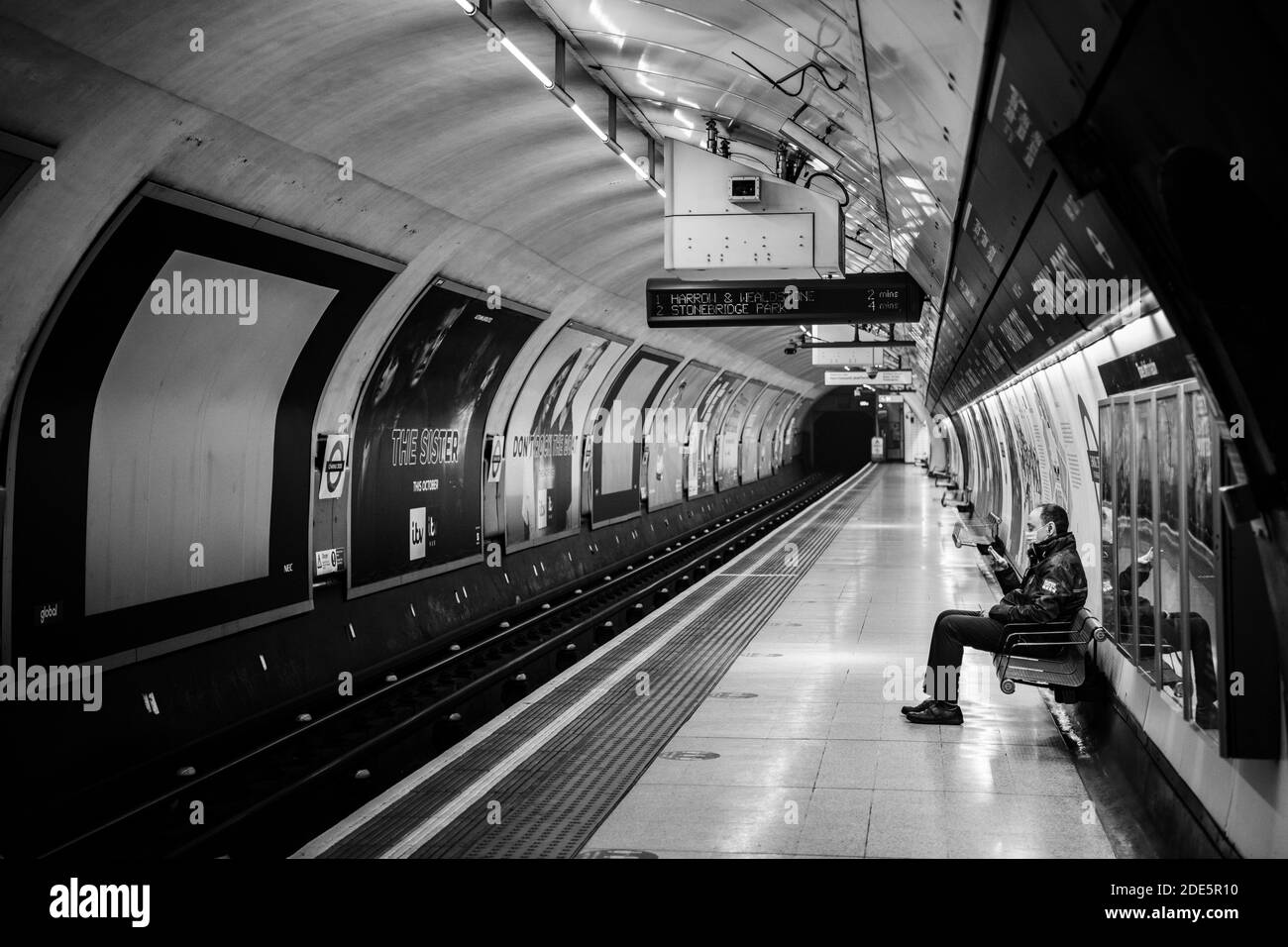 Ruhige, leere Londoner U-Bahn-Station in Coronavirus Covid-19 Pandemiesperre, mit einer einzigen Person auf dem Bahnsteig des öffentlichen Verkehrs während des Reiseverbots Stockfoto