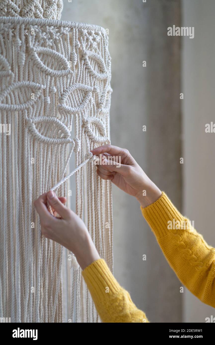 Nahaufnahme der freiberuflichen Frau arbeiten an halb fertig macrame Stück, webt Lampenschirm für Kronleuchter. Frauen Hobby. Stockfoto