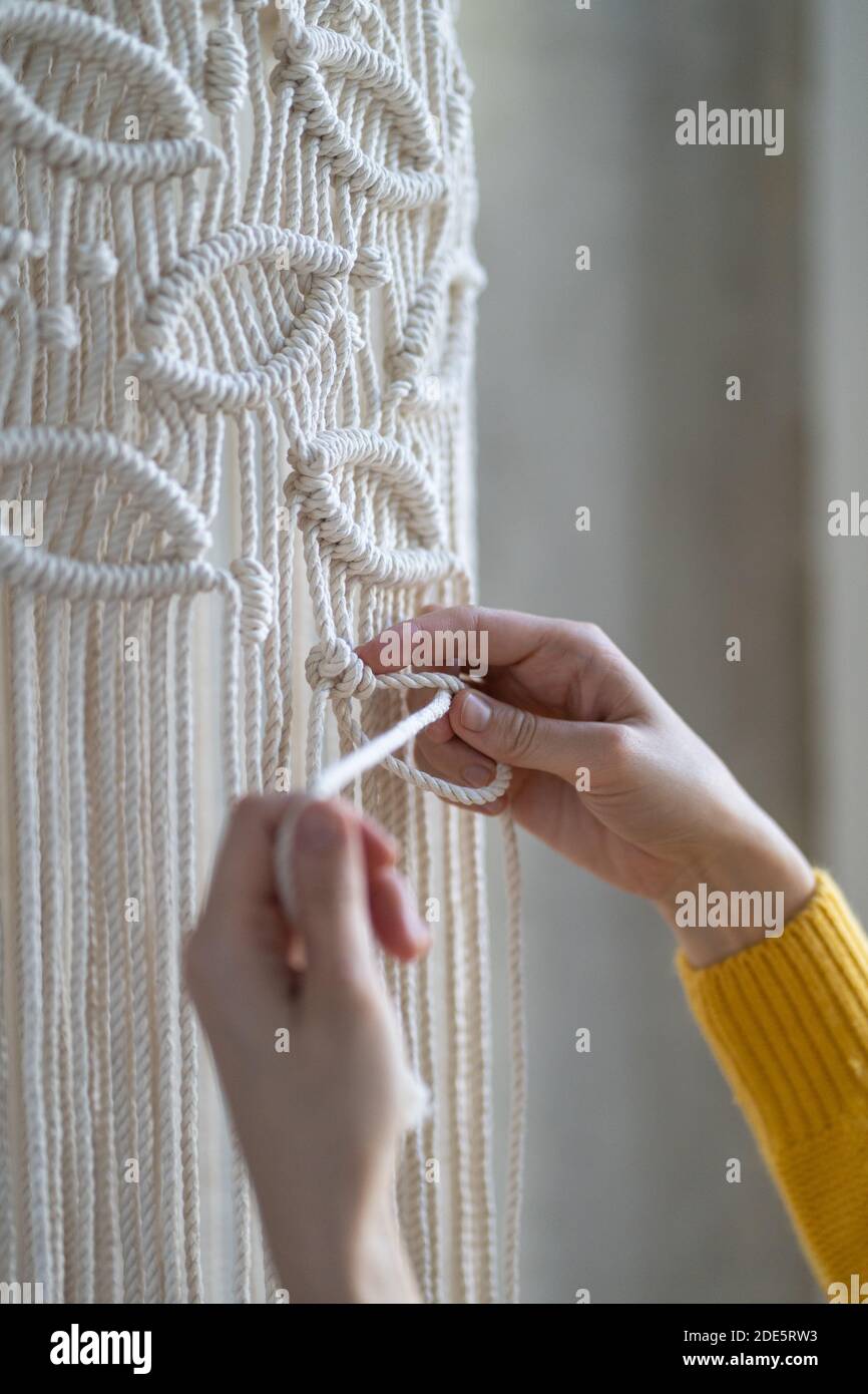 Nahaufnahme der freiberuflichen Frau arbeiten an halb fertig macrame Stück, webt Lampenschirm für Kronleuchter. Frauen Hobby. Stockfoto