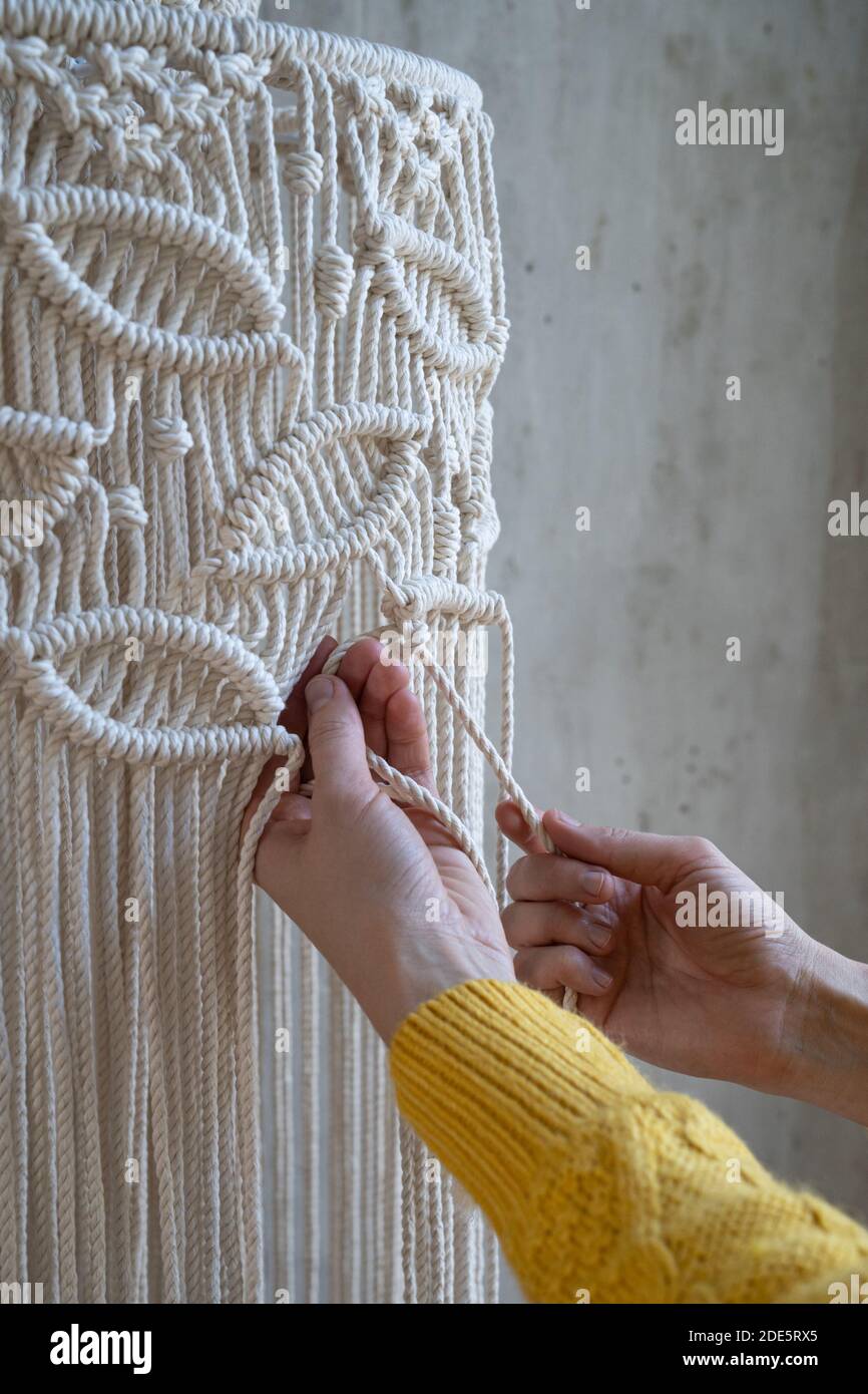Nahaufnahme der freiberuflichen Frau arbeiten an halb fertig macrame Stück, webt Lampenschirm für Kronleuchter. Frauen Hobby. Stockfoto