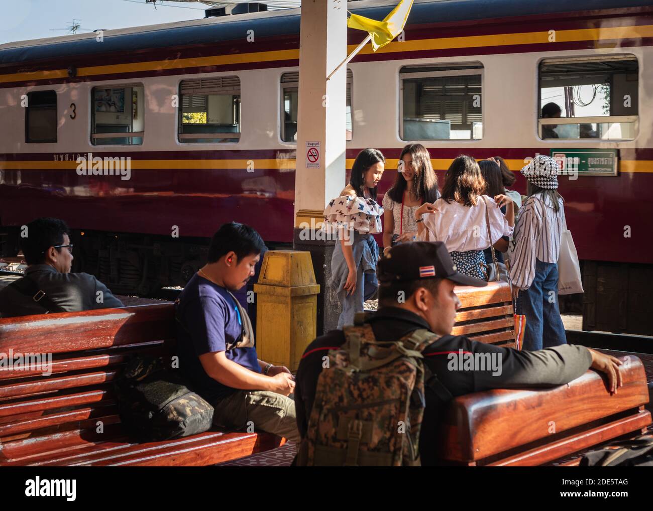 Thailand; Feb 2020: Gruppe von Thai-Mädchen warten auf den Zug an einem thailändischen Bahnhof, Leute warten auf den Zug Abfahrt sitzen auf Holzbänken Stockfoto