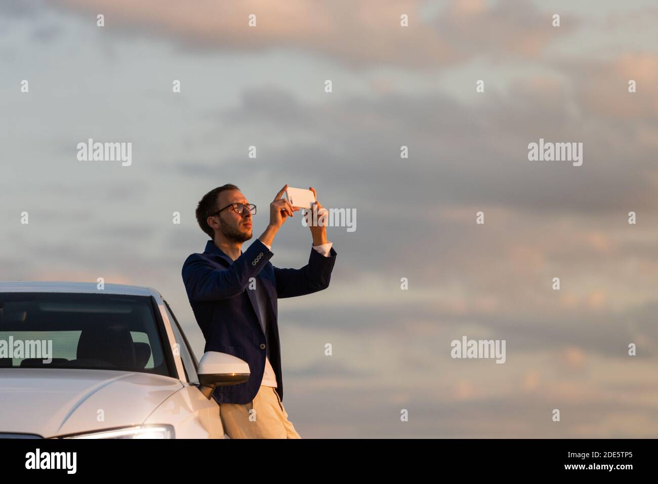 Mann Fahrer hielt an, um ein Foto von Sonnenuntergang mit Handy zu machen. Sommerzeit. Stockfoto