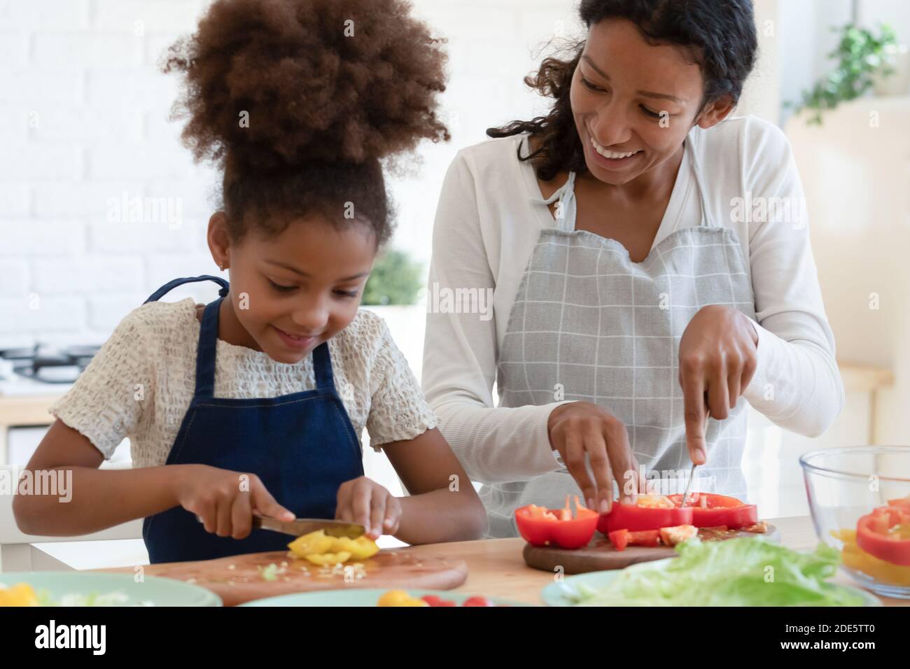 Inspirierte afroamerikanische Mutter und Tochter bereiten veganes Essen zu Stockfoto