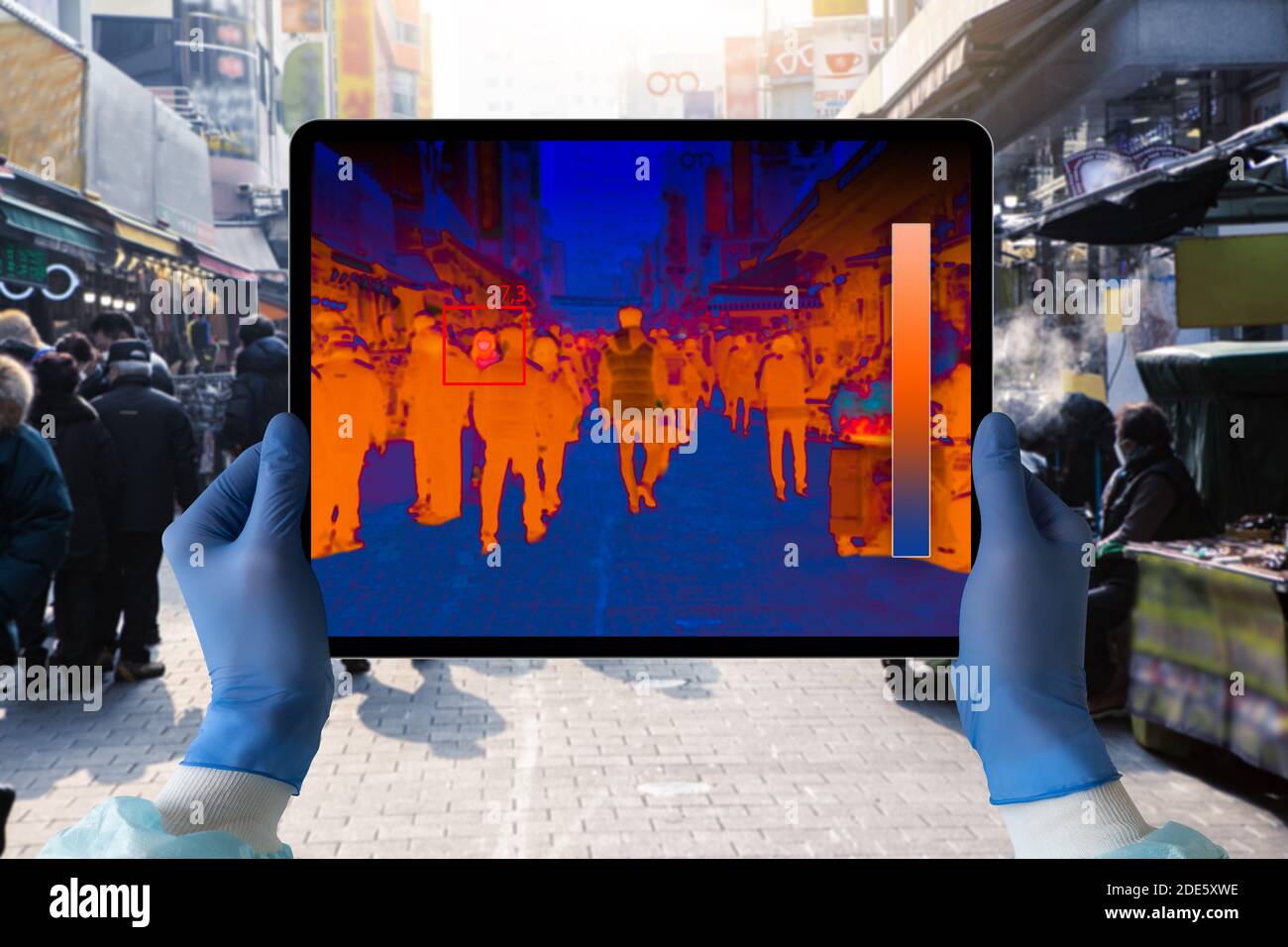 Hände mit digitalem Tablet und Wärmebildkamera. Menschen mit hohem Fieber in der Menge zu finden Stockfoto