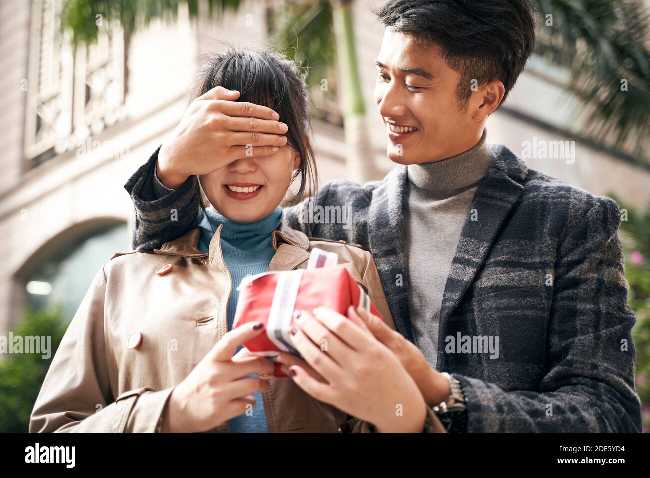 Junge asiatische Mann geben Freundin eine Überraschung präsent im Freien Stockfoto