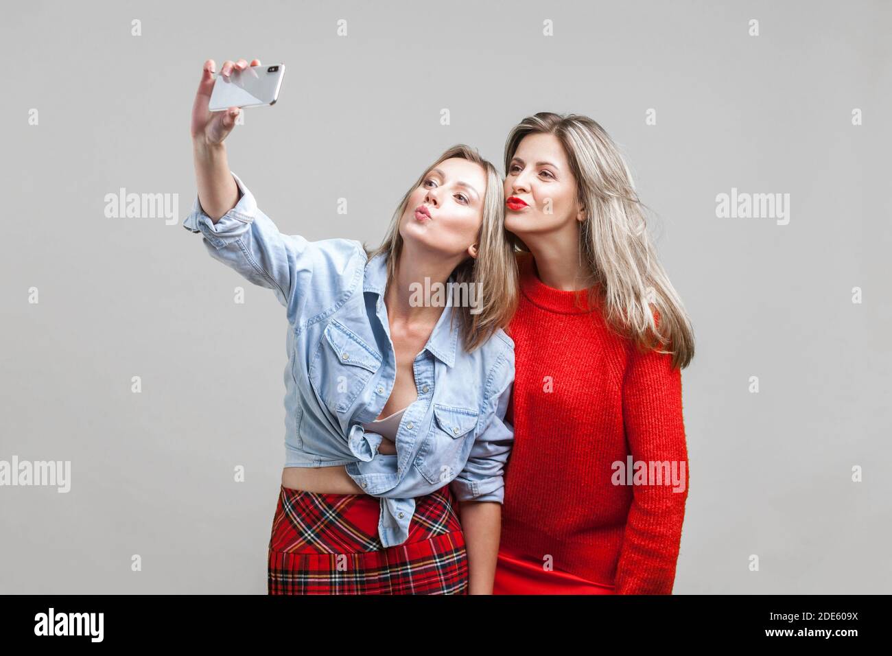 Weibliche Freunde senden Kuss während der Einnahme von selfie. Porträt von zwei attraktive Frauen in der stilvollen Kleidung stehend, mit Smartphone lustiges Foto. Ich Stockfoto