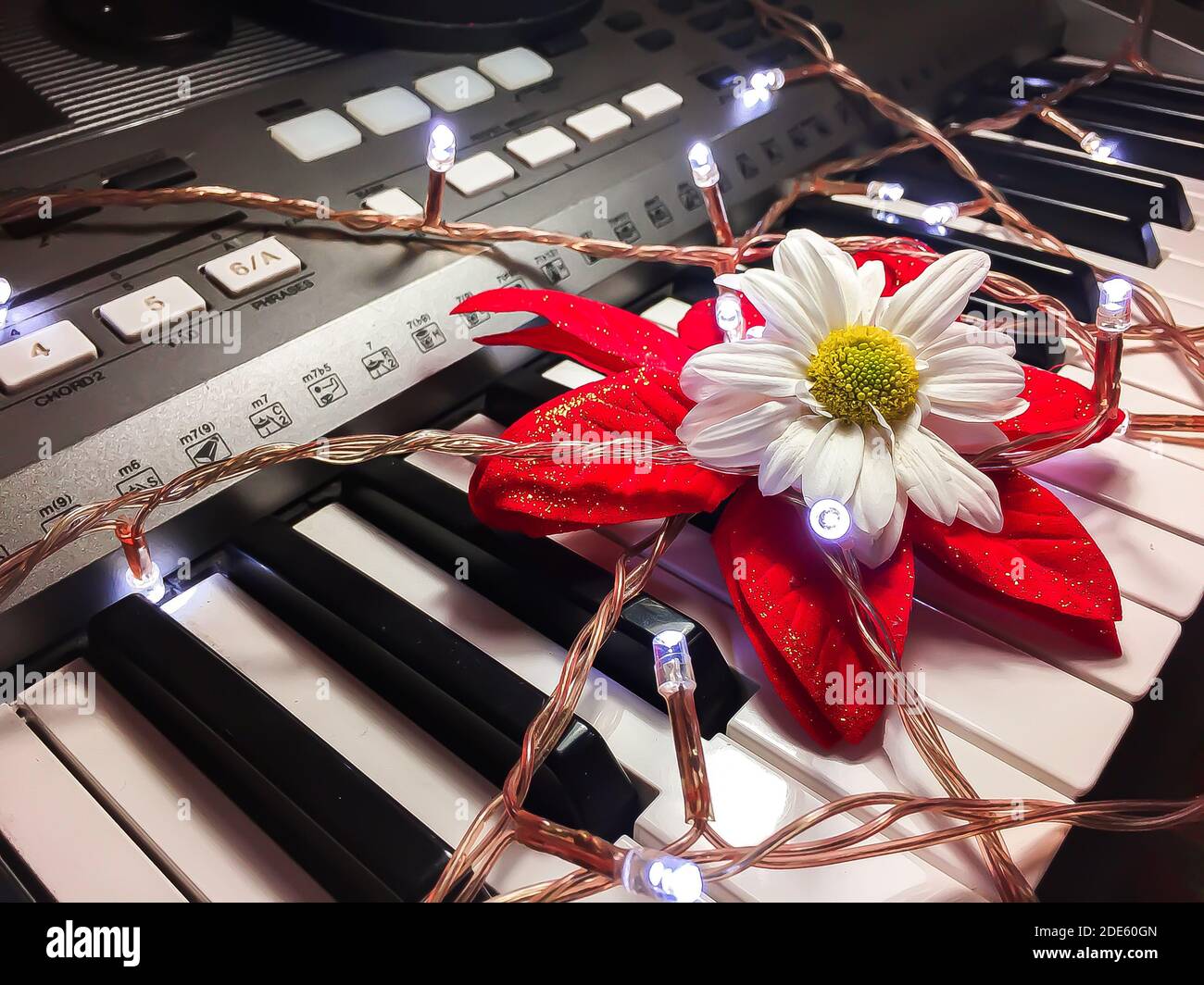 Eine Nahaufnahme von Weihnachtslichtern und eine künstliche Blume an Ein elektronisches Klavier Stockfoto