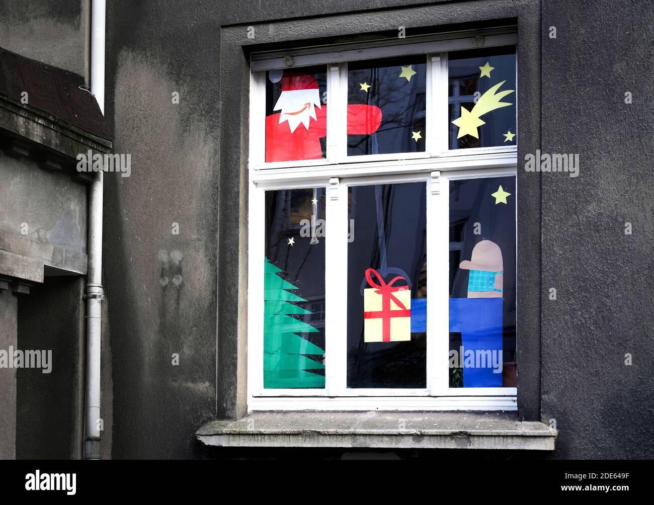 Dortmund, 29. November 2020: Nikolaus mit dem Amazon-Logo als sein Mund das Paket liefert, trägt der gebende Mann Mund- und Nasenschutz gegen das Virus. Apartment Fenster für Weihnachten geschmückt zeigt Heiligabend in Corona Zeiten. Stockfoto