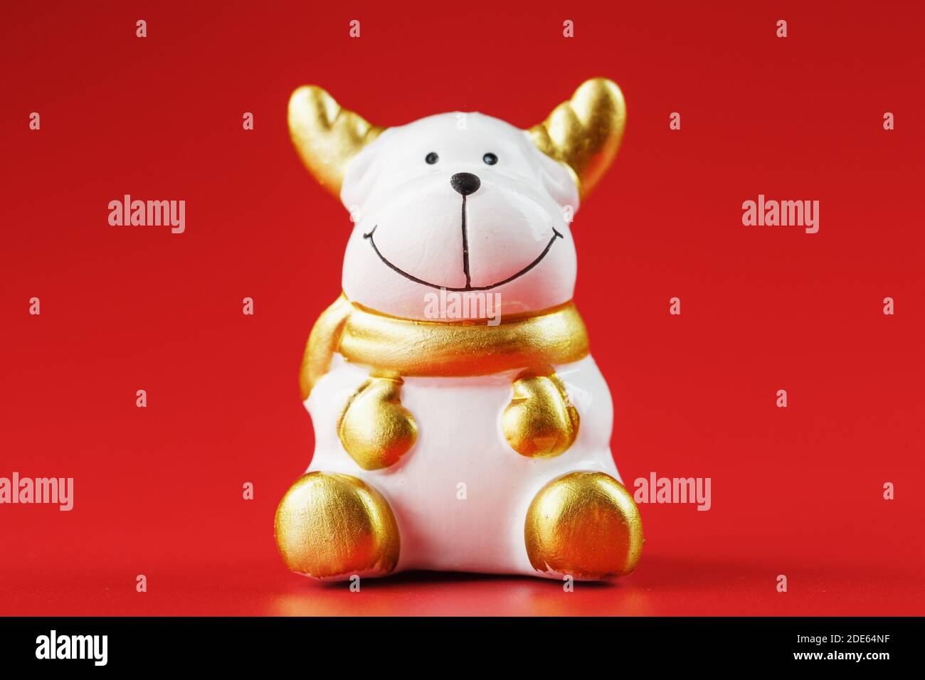 Weihnachtskuhfigur auf rotem Hintergrund. Symbol des neuen Jahres des Bullen 2021. Isolieren Stockfoto