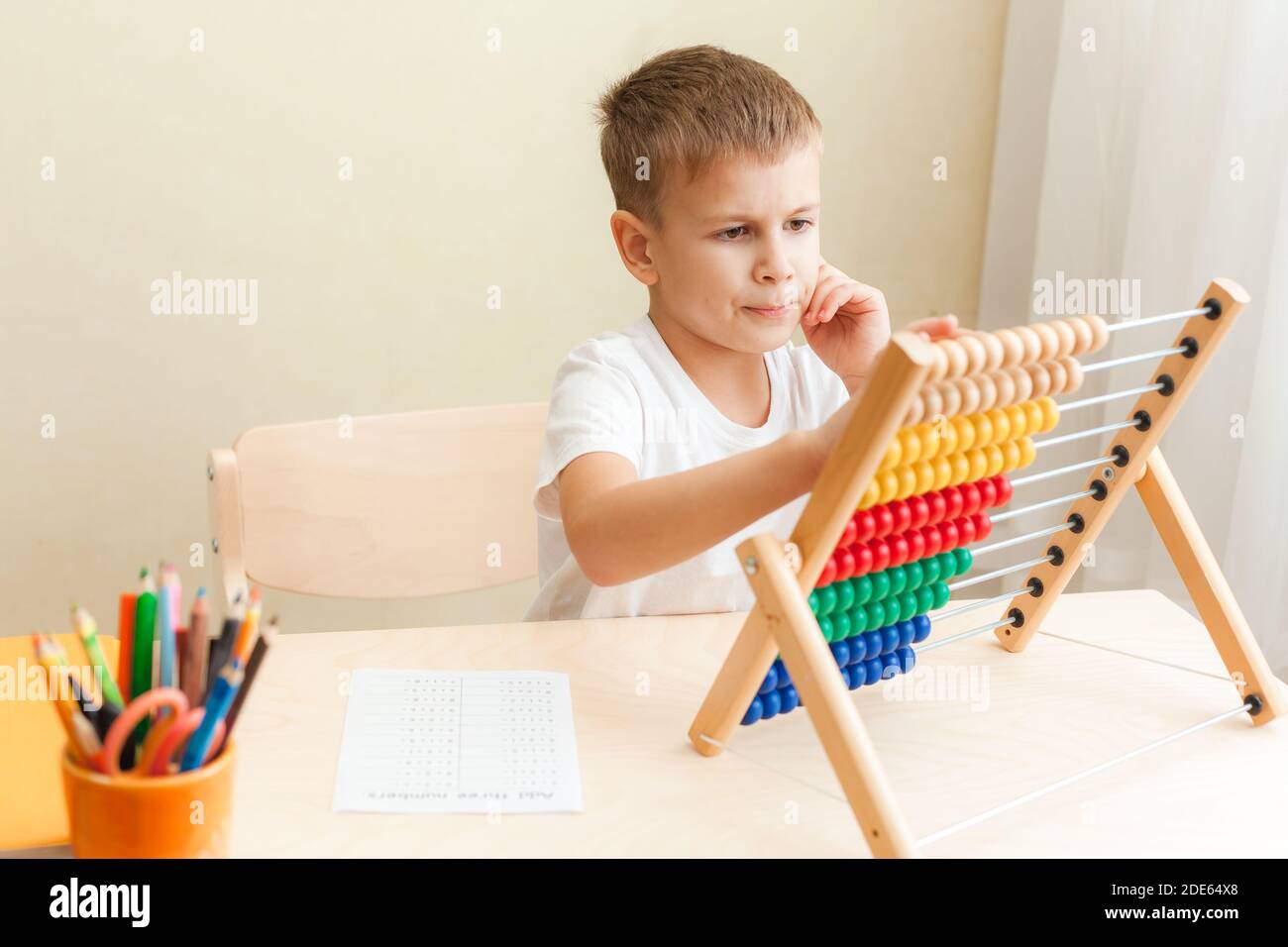 Kinder lösen mathematische Übungen. 7 Jahre alter Junge, der Mathematik-Unterricht macht, sitzt am Schreibtisch in seinem Zimmer. Stockfoto