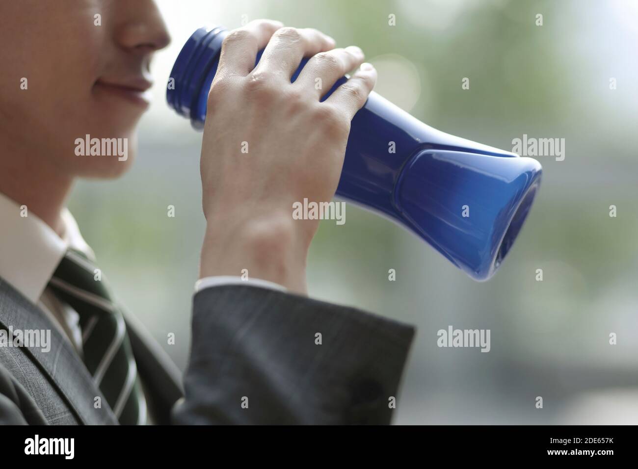 Nahaufnahme eines Geschäftsmannes, der eine Flasche Wasser trinkt Stockfoto
