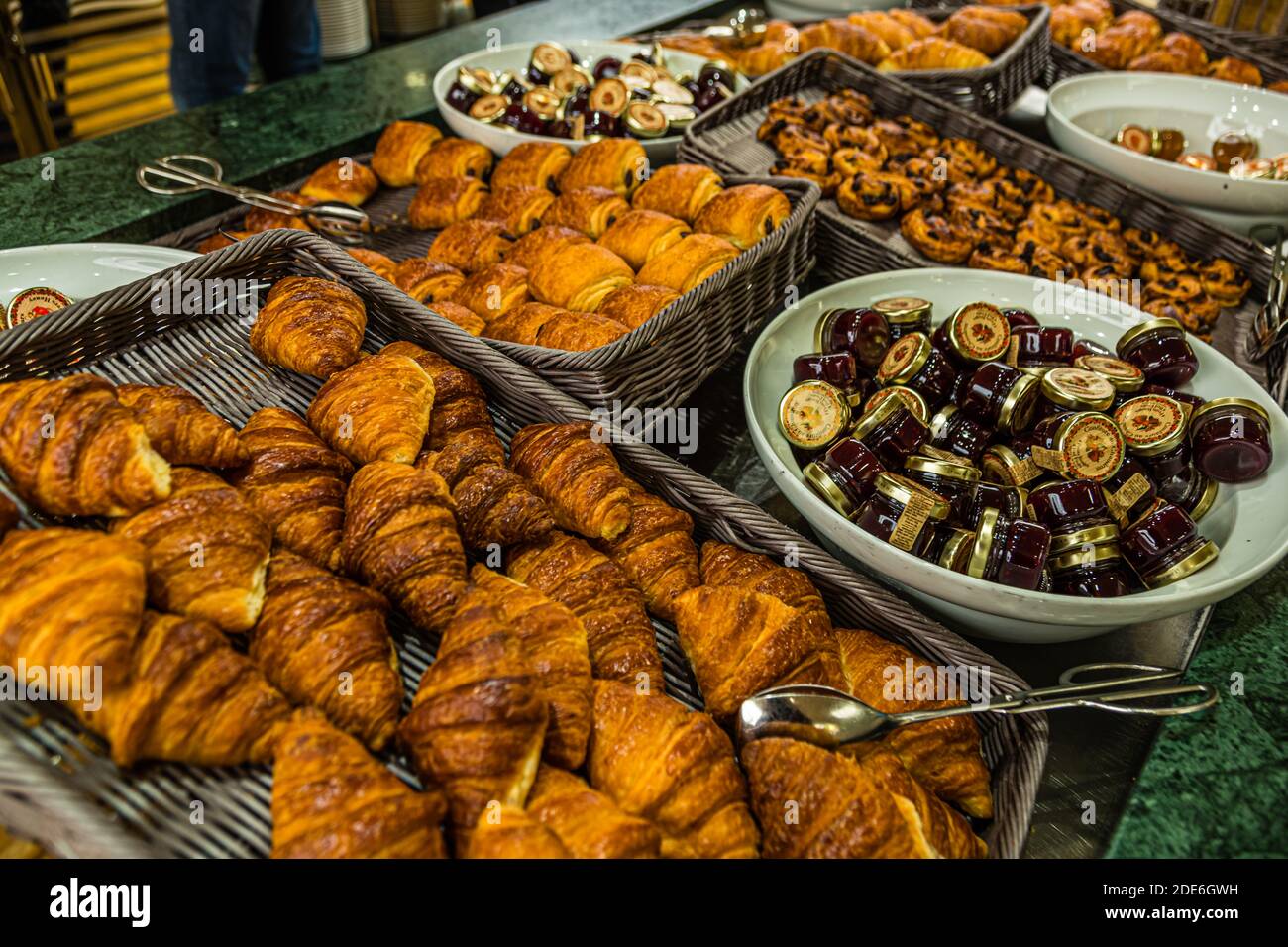 Croissants und verschiedene goldgelbackene Gebäckstücke liegen in Körben auf dem Frühstücksbuffet des Pont Aven von Brittany Ferries, neben Schüsseln mit kleinen Marmeladengläsern. Stockfoto
