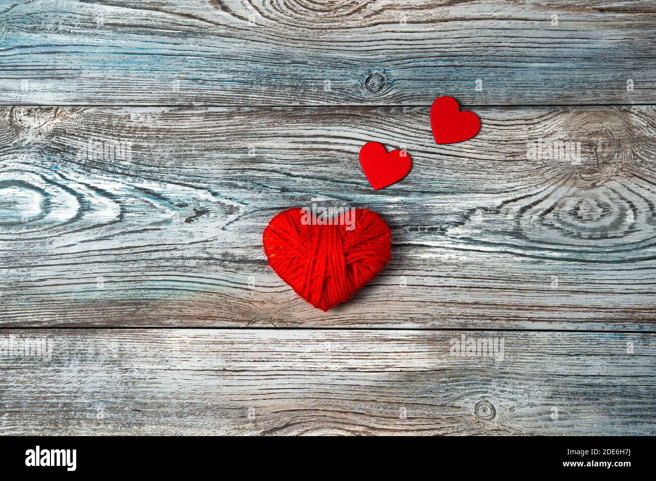 Rote Herzen auf einem grau-blauen Hintergrund aus Holz. Stockfoto