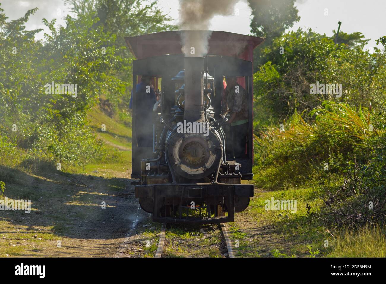 Ein alter Dampfzug fährt auf einer Bahnlinie, die einst Zuckerrohr in Kuba transporte und heute für Vergnügungsfahrten für Touristen genutzt wird, durch die Landschaft Stockfoto