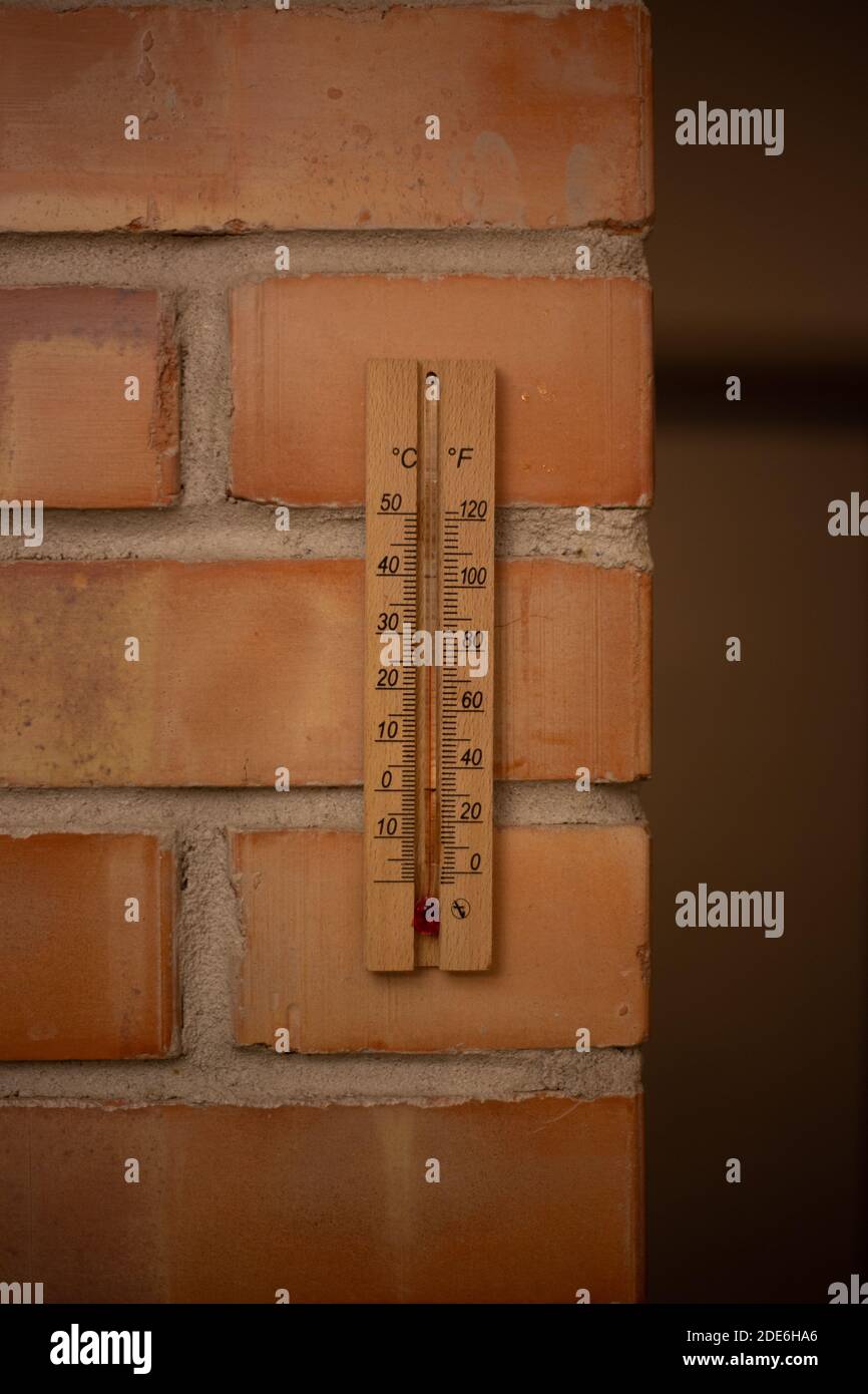 Hölzernes Thermometer auf einer Ziegelwand Stockfoto