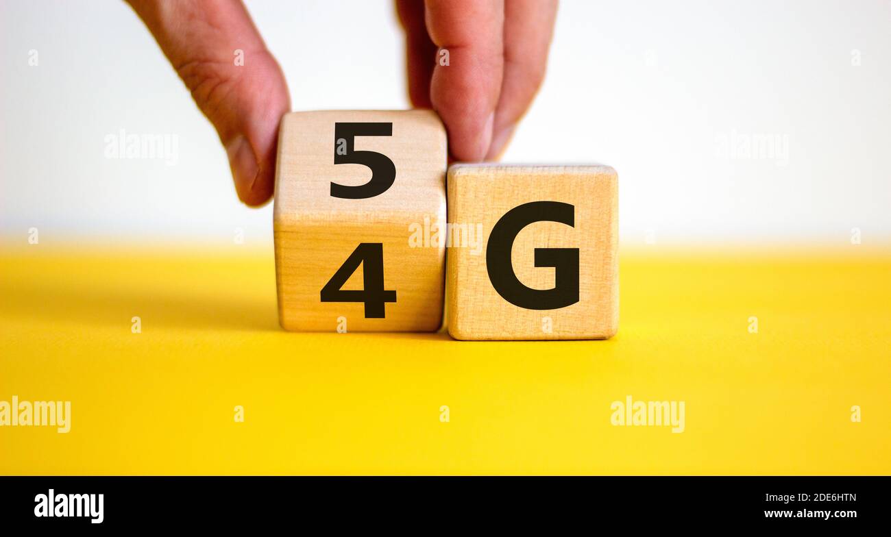 Zeit bis 5G. Männliche Hand dreht Holzblock und ändert Zeichen 4G auf 5G. Technologie, Netzwerk, Kommunikationskonzept. Schöner gelber Tisch. Weißer Hintergrund Stockfoto