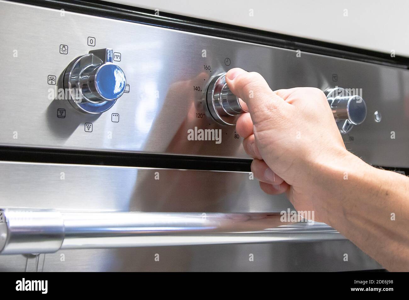Die Hand eines Mannes dreht den Kippschalter am Herd. Stockfoto