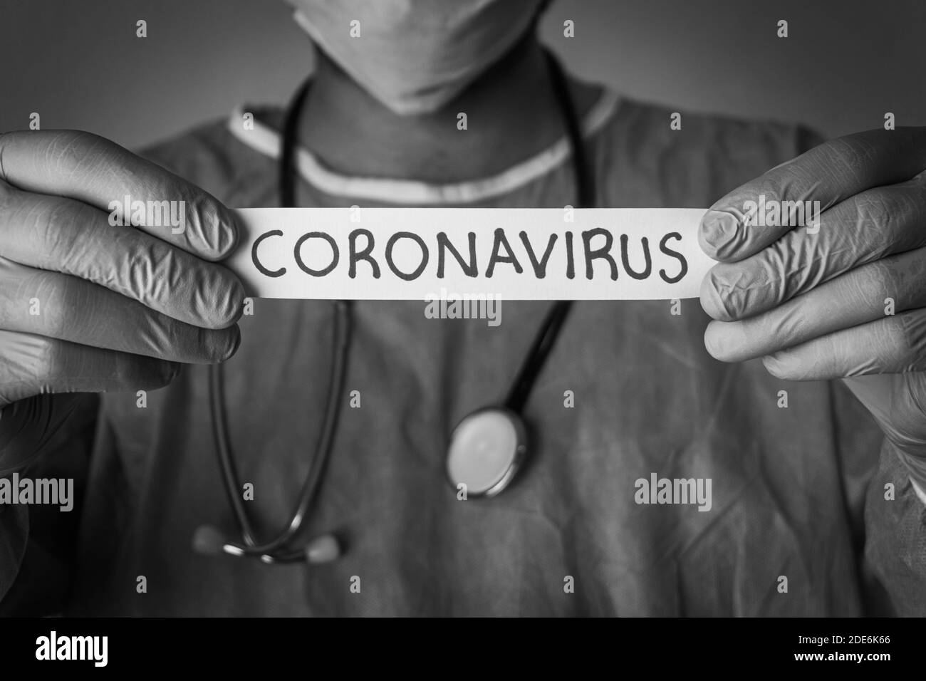 Arzt hält ein Papier, das Coronavirus geschrieben. Covid-19 Konzept und Hintergrund. Schwarzweiß-Foto. Stockfoto