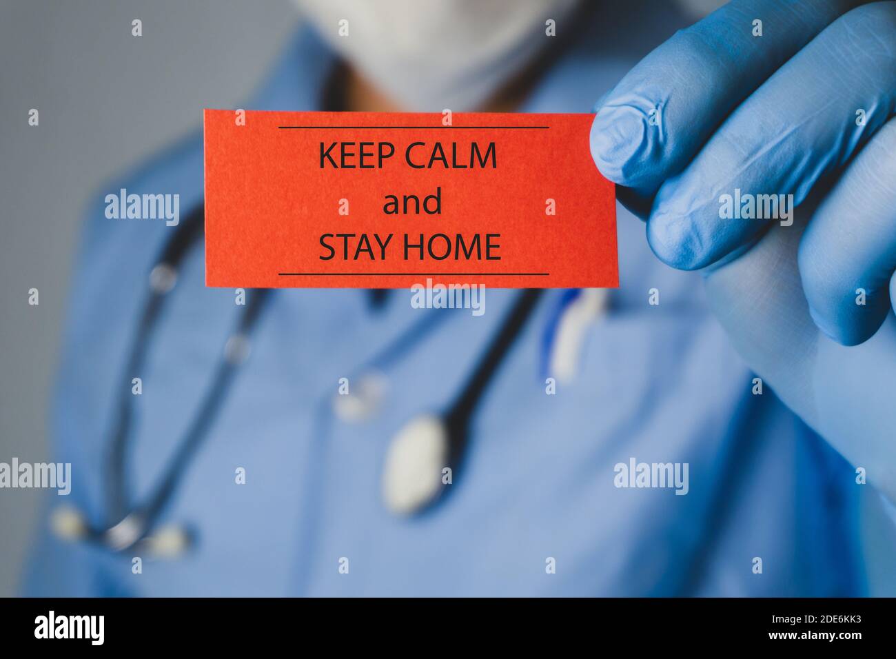Coronavirus-Konzept. Arzt hält ein rotes Papier, das geschrieben zu Hause bleiben. Stockfoto
