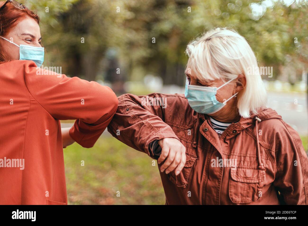 Ellenbogenstoß. Zwei Menschen stoßen Ellbogen, um Coronavirus im Freien zu vermeiden. Menschen, die Spaß zusammen haben Stockfoto