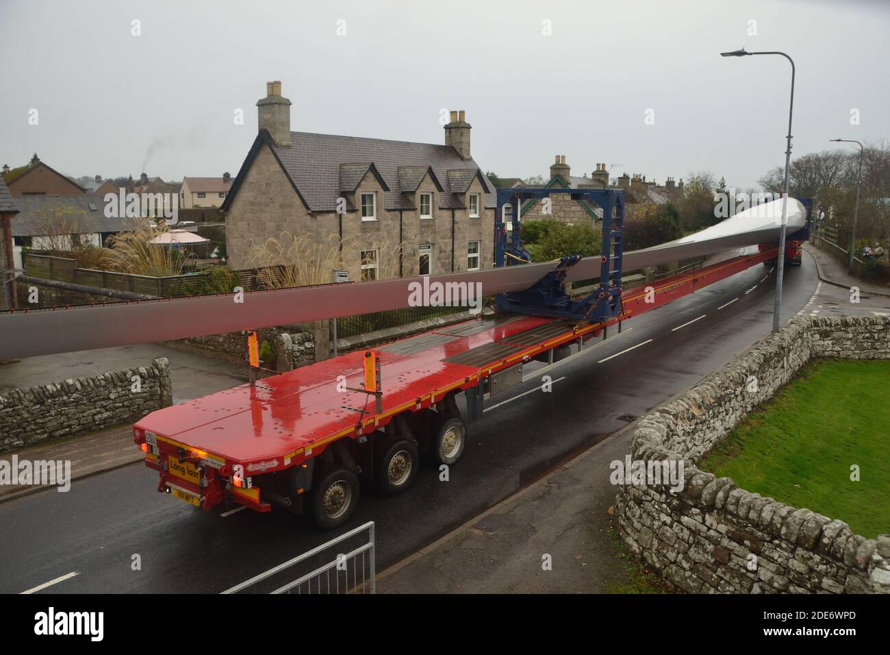 Ein Rotorblatt wird auf einem extra langen LKW zur Lieferung an den Windpark Gordonbush transportiert, wie auf der A9 in Golspie, schottische Highlands, zu sehen ist. Stockfoto