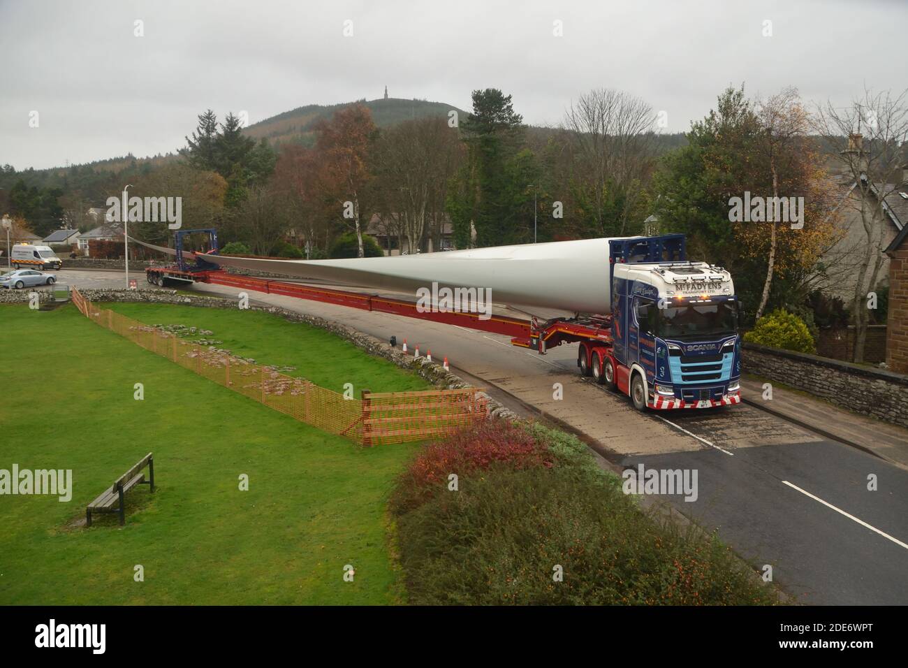 Ein LKW, der ein Turbinenblatt für einen Windpark transportiert Die Verhandlung einer Kurve auf der Straße durch das Dorf von Golspie in den schottischen Highlands Stockfoto