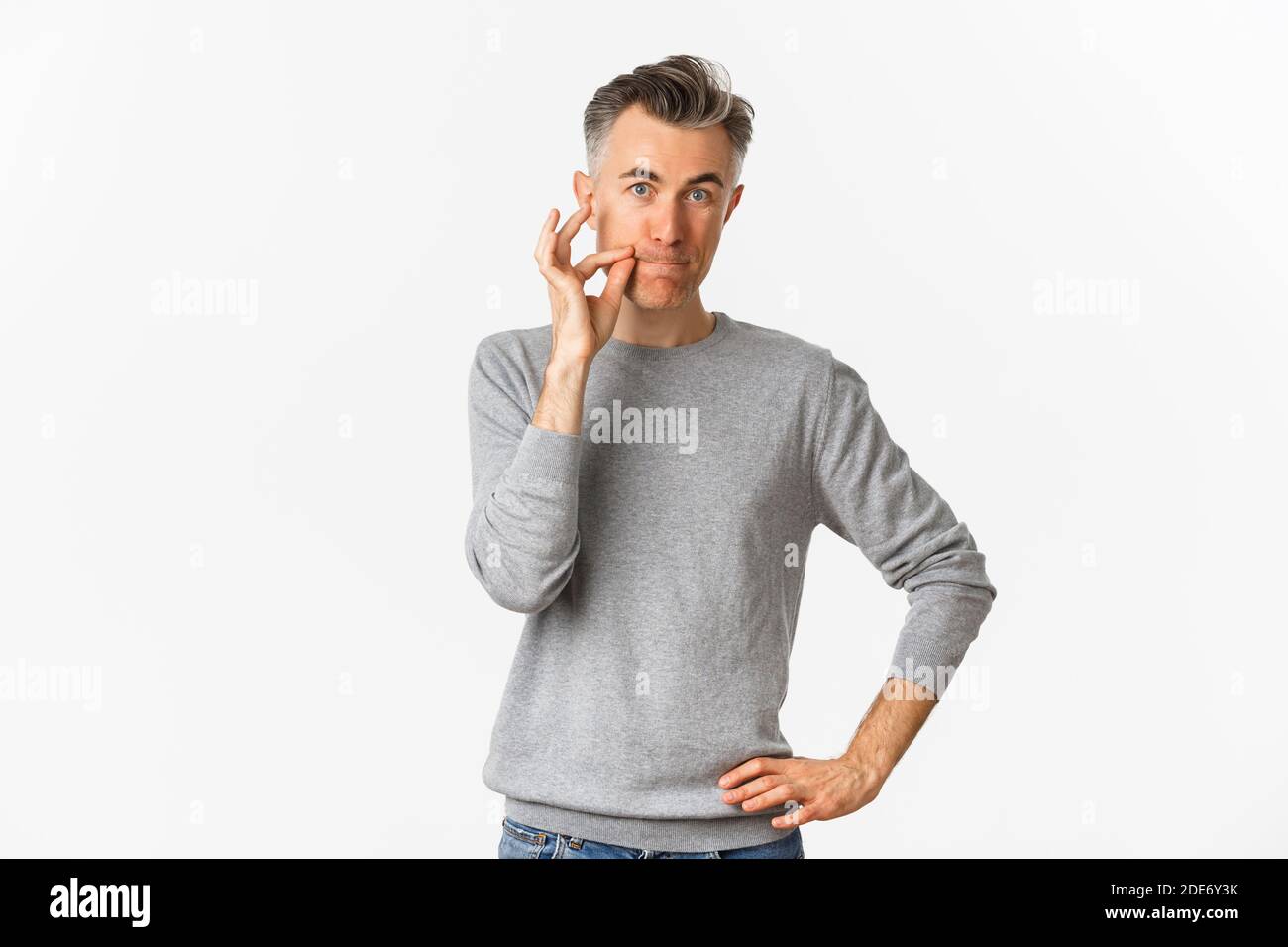 Portrait von Mann mittleren Alters, die Versprechen zu halten Mund geschlossen, Zippen Lippen, Geheimnis versteckt, stehen auf weißem Hintergrund Stockfoto