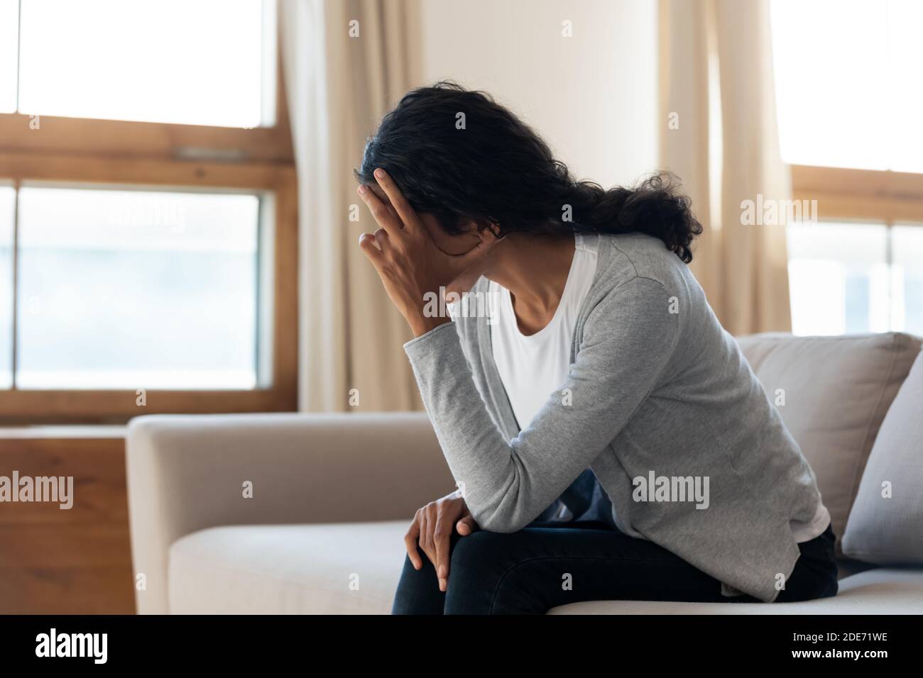 Unglückliche Frau sitzt zu Hause und fühlt sich deprimiert Stockfoto