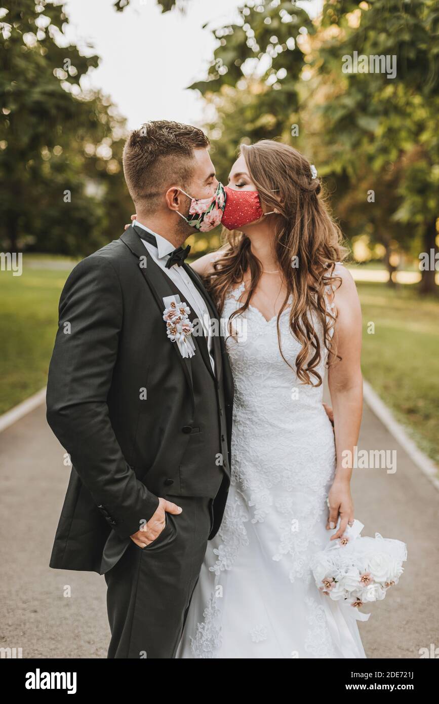Brautpaar mit Gesichtsmaske in covid-19 Coronavirus Zeit Liebe Stockfoto
