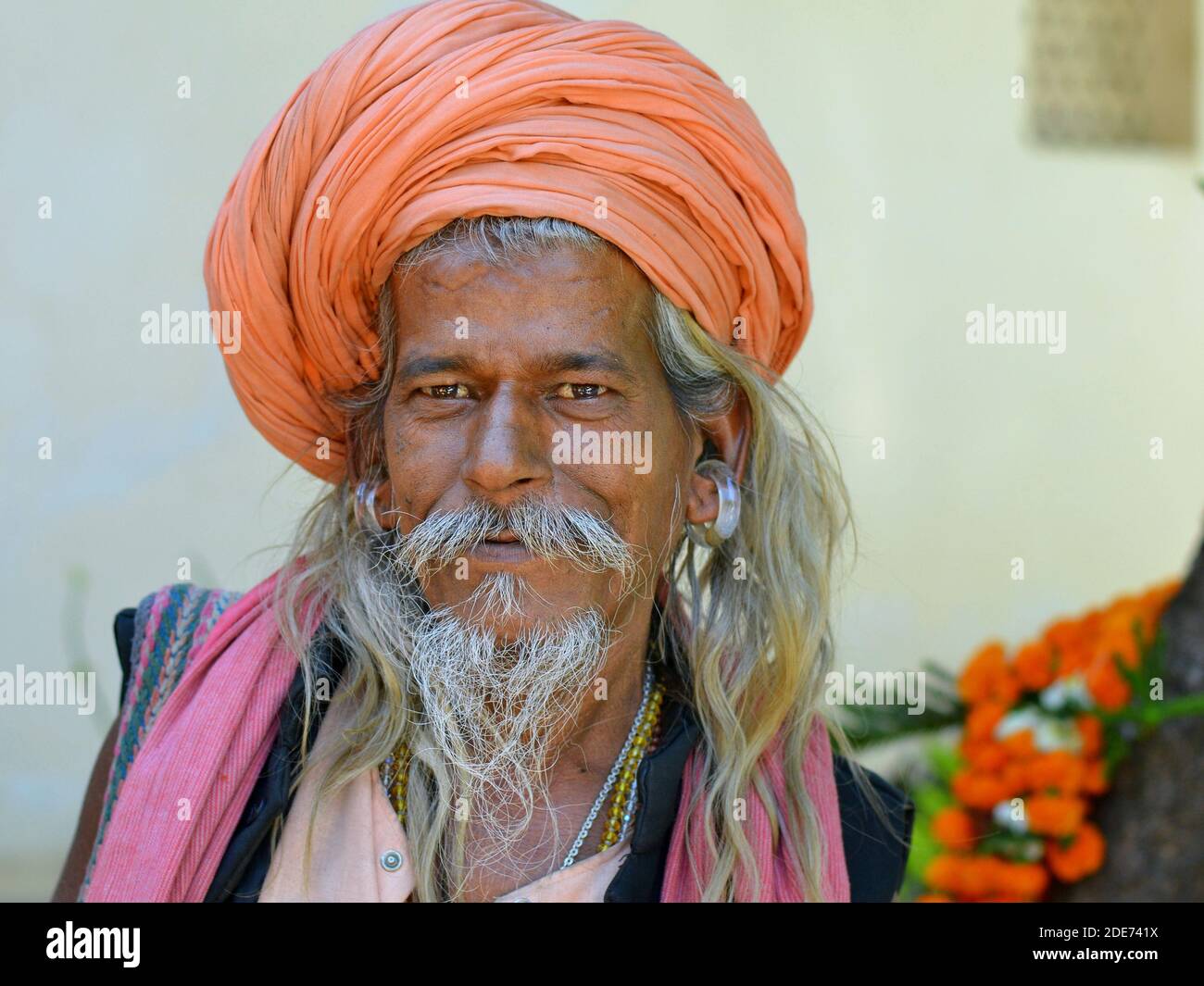 Positiv freundlich geturbter Gorakhnathi (Kanphata) Yogi Mönch mit den massiven Ohrringen des religiösen Gorakh-Nath Hindu Ordens lächelt an der Kamera. Stockfoto