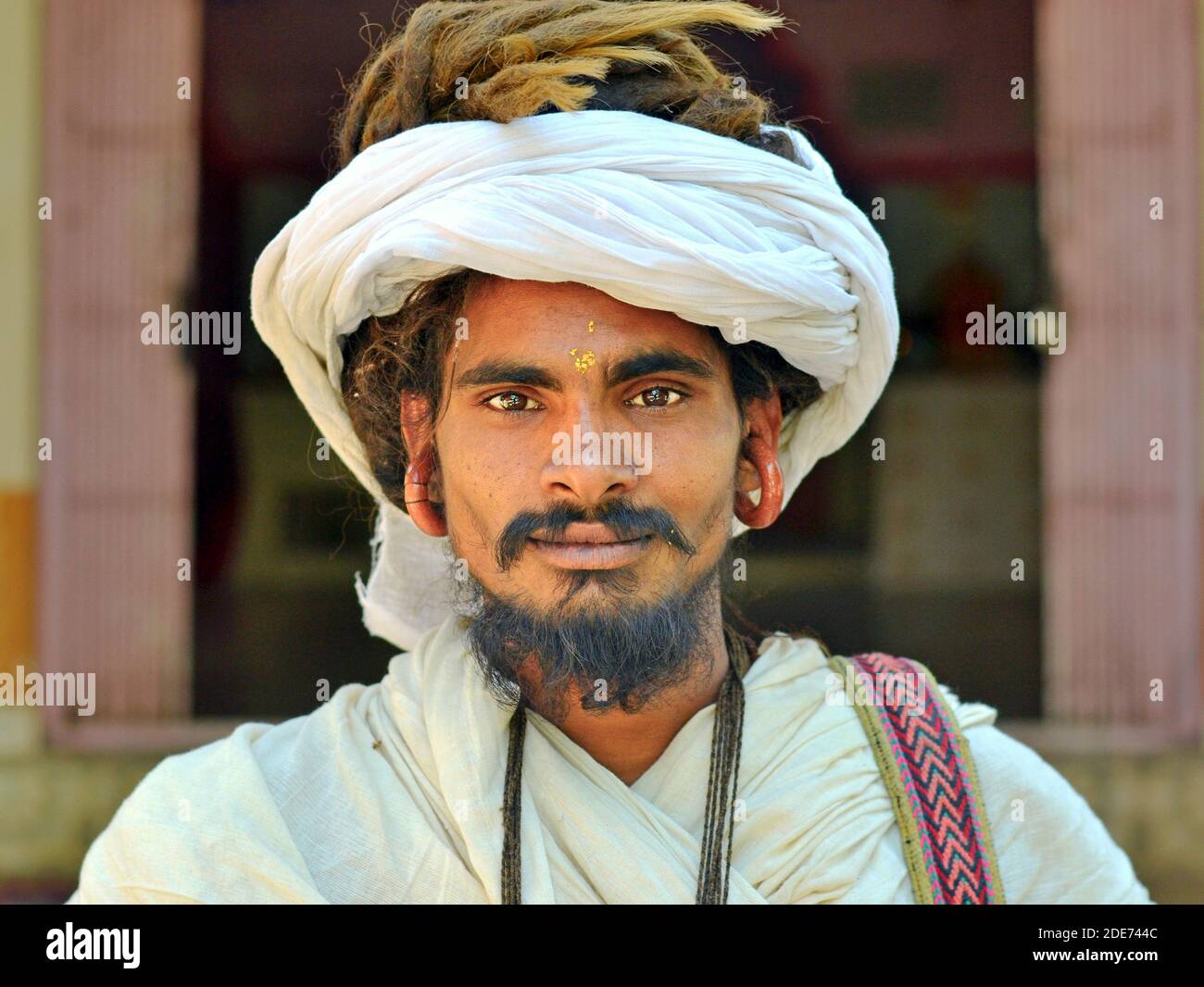 Turbanierter junger Gorakhnathi (Kanphata) Yogi Mönch mit Dreadlocks und die massiven Ohrringe des religiösen Gorakh-Nath Hindu Ordens posiert für die Kamera. Stockfoto