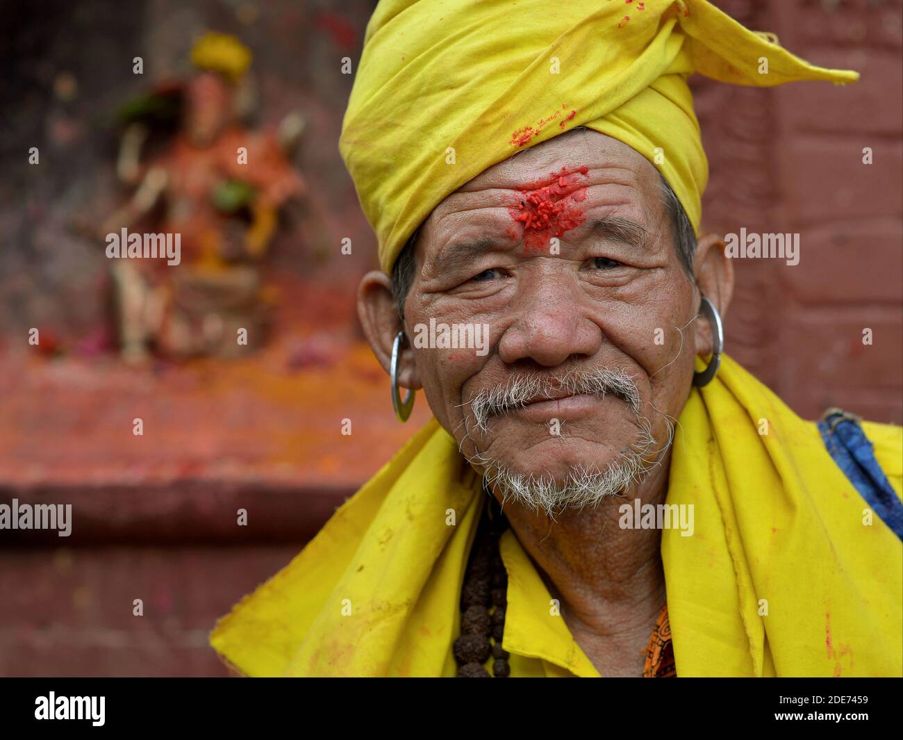 Älterer nepalesischer Hindu Gorakhnathi (Kanphata) Yogi Mönch mit großen Metallohrringen und roter Reiskleie auf der Stirn stellt sich für die Kamera. Stockfoto