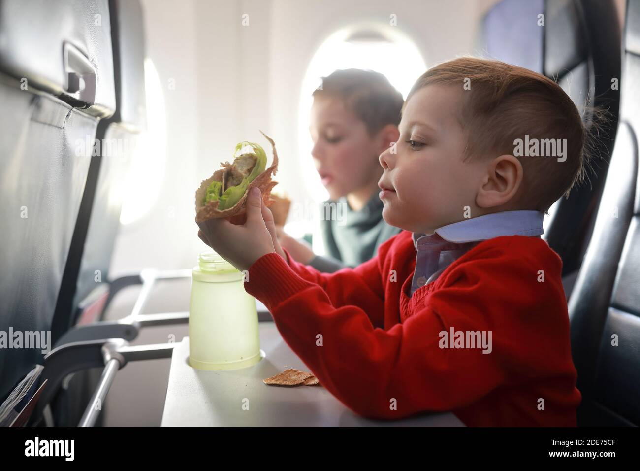 Porträt von Kindern essen im Flugzeug Stockfoto