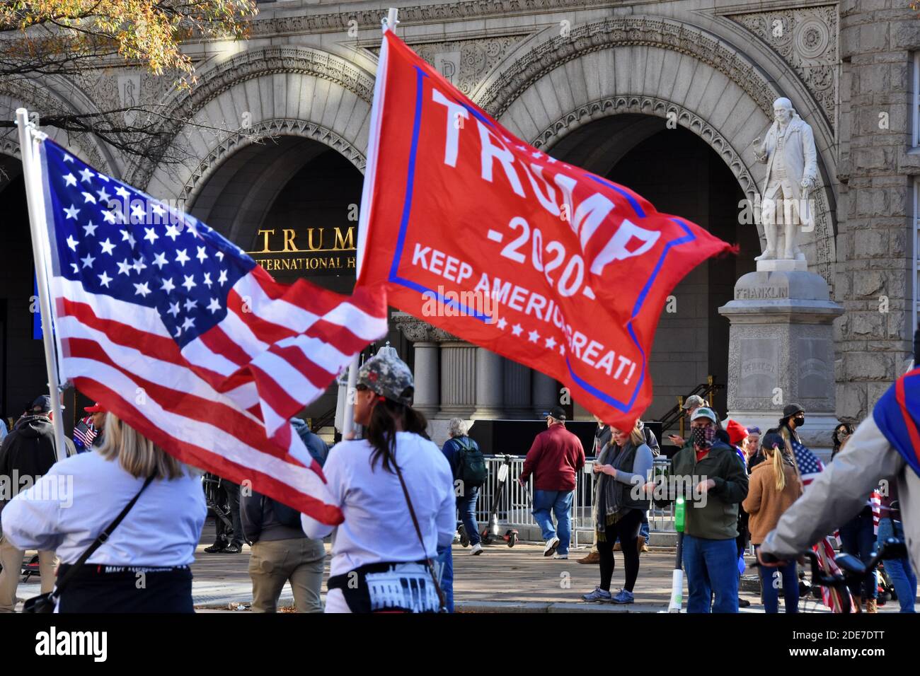 Washington DC. November 2020, 14. Million Maga Marsch. Frauen mit amerikanischer Flagge und „Trump Keep America Great“-Flagge vor dem Trump International Hotel. Stockfoto