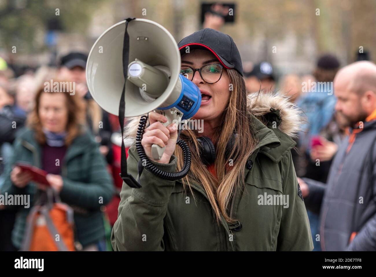Weiße kaukasische Frau schreit durch ein Megaphon auf einem COVID 19 Coronavirus Anti-Lockdown-protestmarsch in London, Großbritannien. Illegale Erfassung Stockfoto