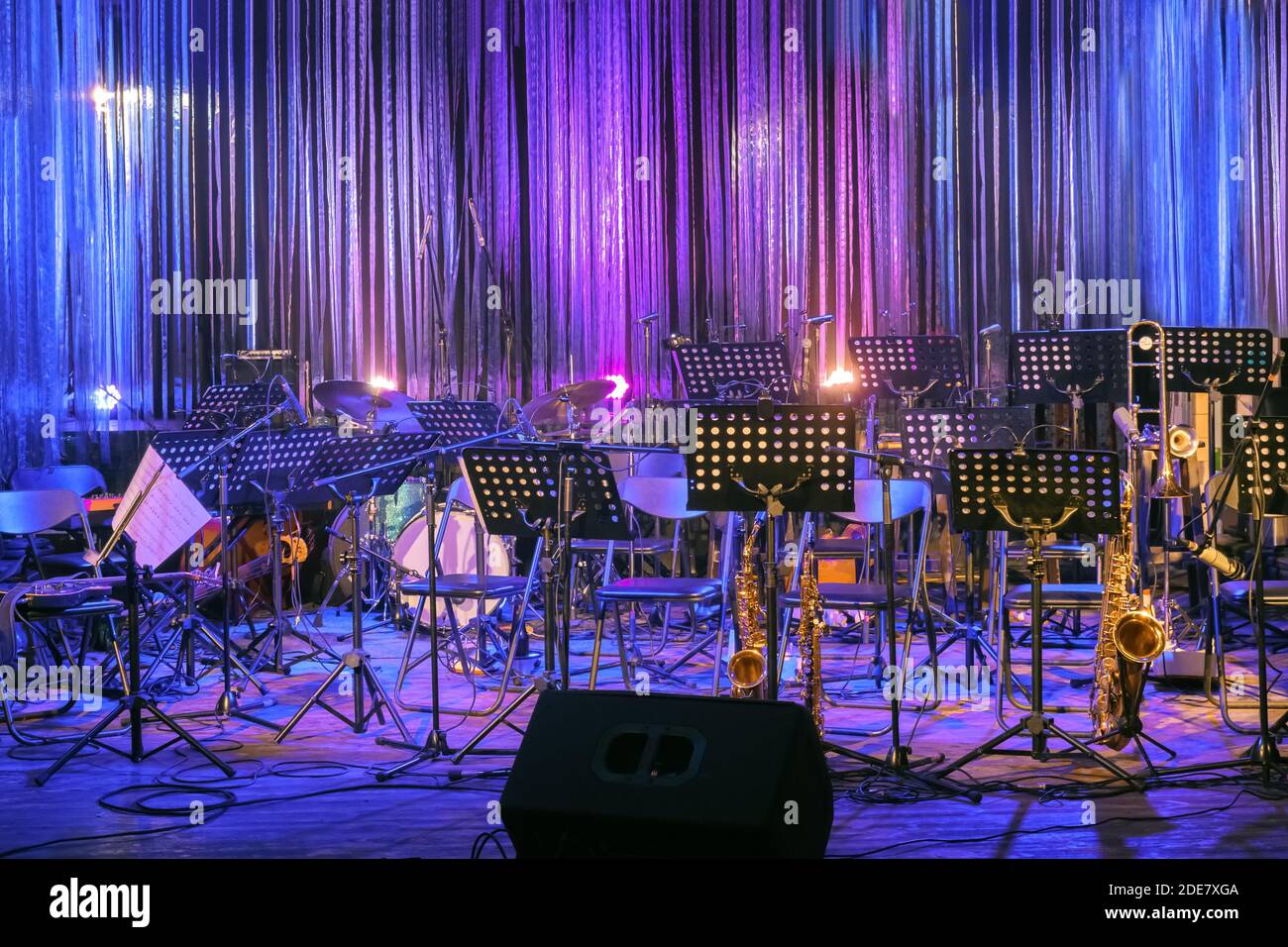 Musikinstrumente und Notenblätter bereit auf einer Bühne für eine Live-Performance bei Rock oder Jazz Konzert oder Festival in bunten Licht. Leer Stockfoto