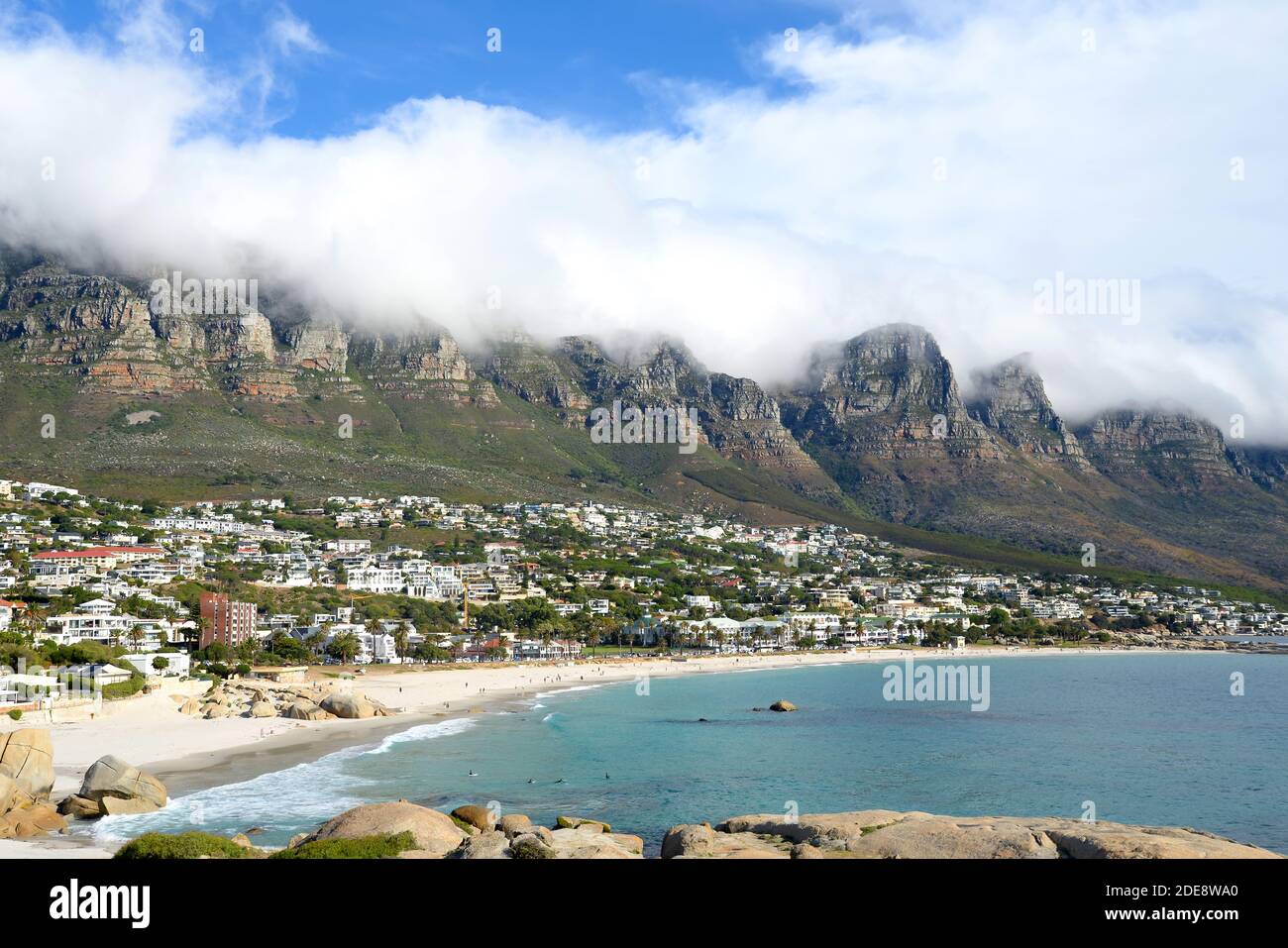 Glen Beach und Camps Bay Beach in Kapstadt, Südafrika mit zwölf Aposteln bedeckt von Wolken dahinter. Strand in Südafrika. Stockfoto