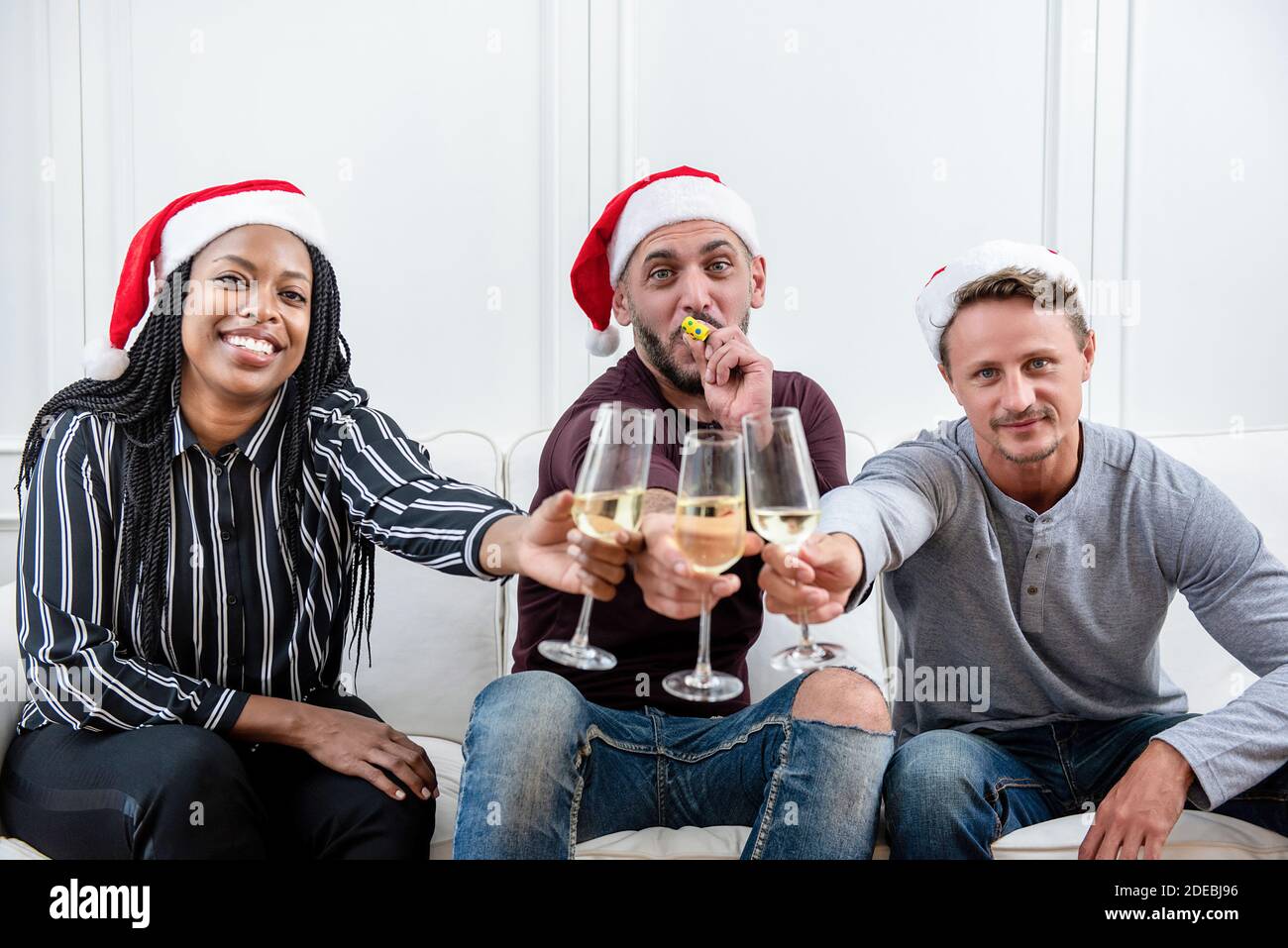 Eine Gruppe von Freunden, die zu Hause Weihnachten feiern und Champagner trinken Der Couch Stockfoto