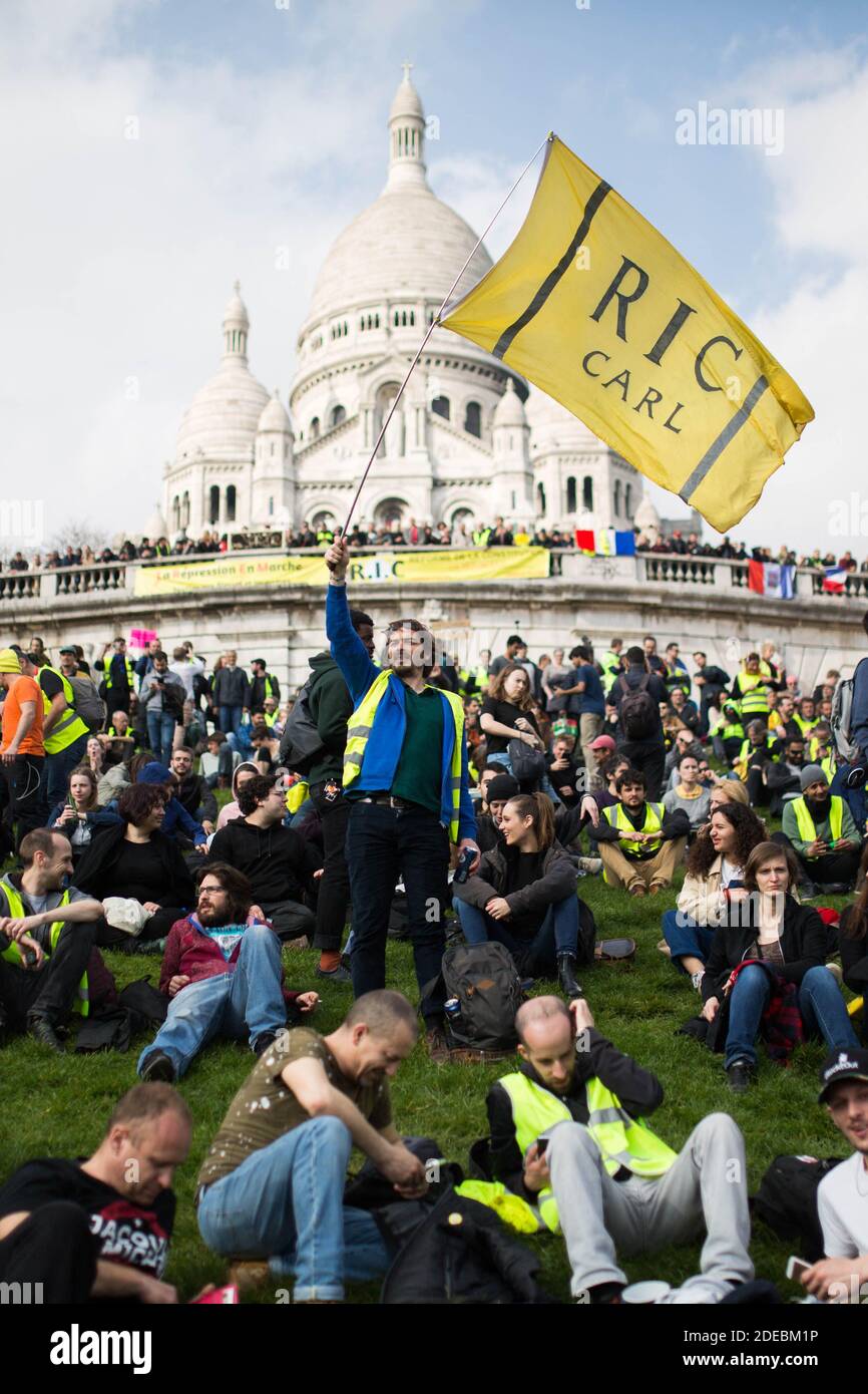 Gelbe Weste Demonstranten versammeln sich vor der Basilika Sacre Coeur in Montmartre, Protestler halten eine gelbe Flagge für die R.I.C., Referundum d'Initiative citoyenne, in Paris am 23. März 2019, während einer Anti-Regierung Demonstration von der "Gelbe Weste" (Gilets jaunes) Bewegung aufgerufen. Am 23. März trafen Demonstranten erneut in den Straßen Frankreichs ein, um eine 19. Woche in Folge landesweit gegen die 19 Politik des französischen Präsidenten und seinen Regierungsstil von oben nach unten, hohe Lebenshaltungskosten, staatliche Steuerreformen und für mehr "soziale und wirtschaftliche Gerechtigkeit" zu protestieren. Foto: Raphael Lafargue/ABACAPRES Stockfoto