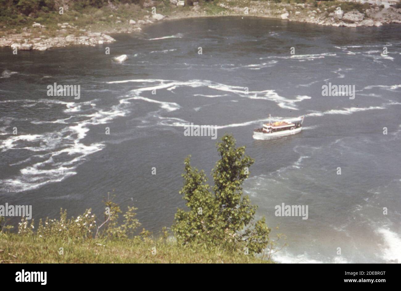 Foto der 1970er Jahre (1973) - Diesel-angetriebenes Schiff der Mist-Stadtbesichtigung fährt den Niagara River direkt unter den Wasserfällen. Das Schaummuster weist auf Verschmutzung durch Abwasser und andere Abfälle hin Stockfoto