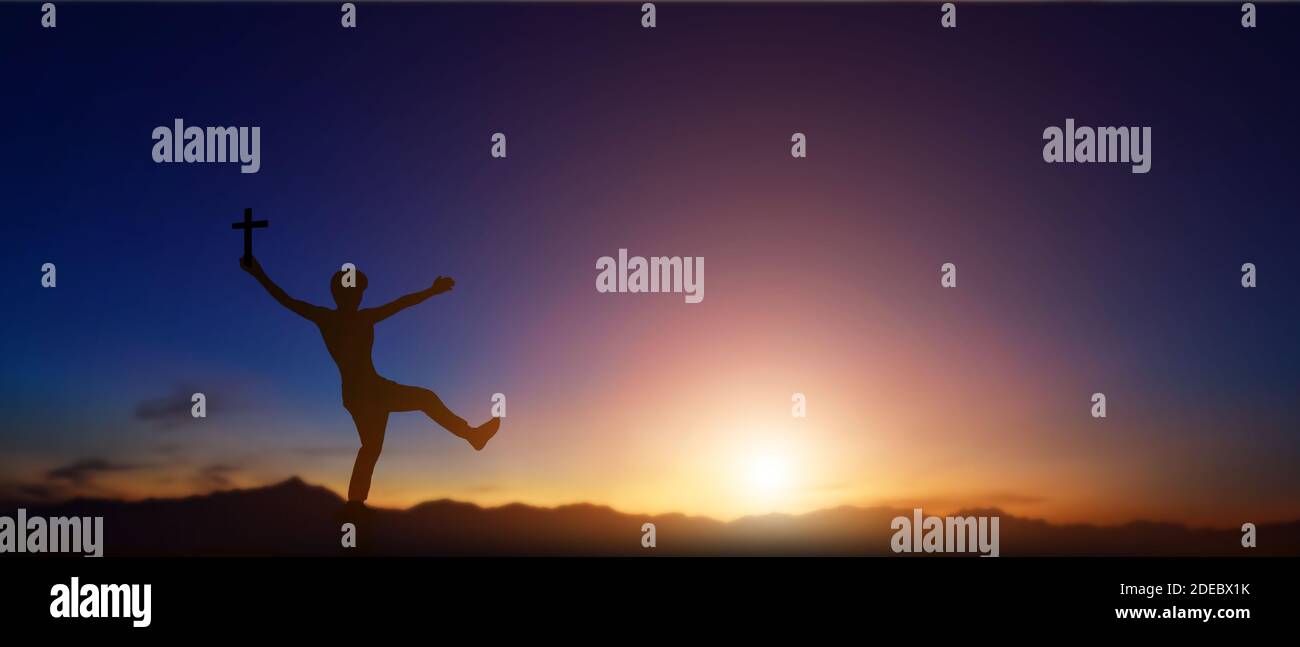 Silhouette des Mannes hält christian Kreuz in den Händen bei Sonnenuntergang Hintergrund. Stockfoto