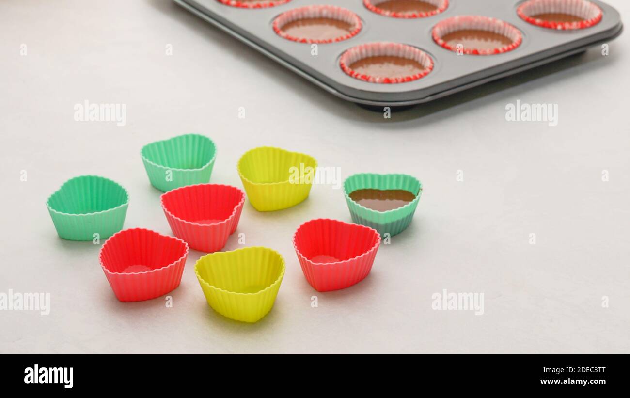 Ausgekleidete Cupcake-Pfanne und Silikonformen aus nächster Nähe auf dem Küchentisch. Backprozess, Schokolade Cupcakes Schritt für Schritt Rezept Stockfoto