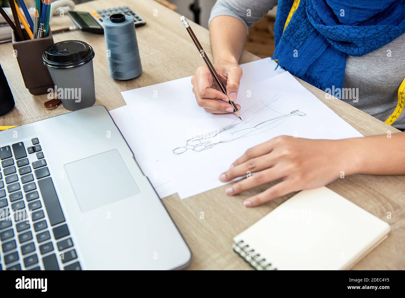 Muslimische Frau Modedesignerin Zeichnung ein Kleid Design Skizze in Papier am Tisch Stockfoto