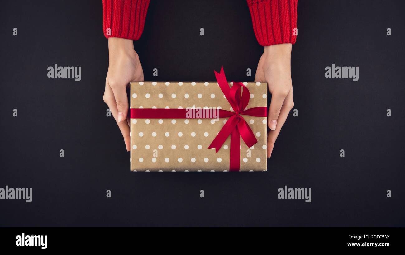 Frau Hände geben christsmas Geschenkbox Draufsicht auf schwarz Hintergrund Stockfoto