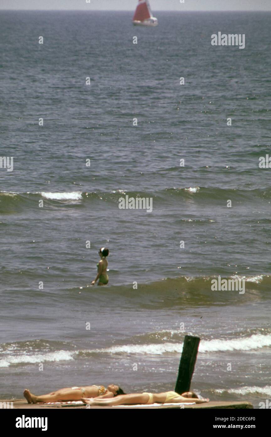 1970er Foto (1973) - Sonnenanbeter, Schwimmer, Segelboot - Blick von West Beach auf den Golf von Mexiko Stockfoto
