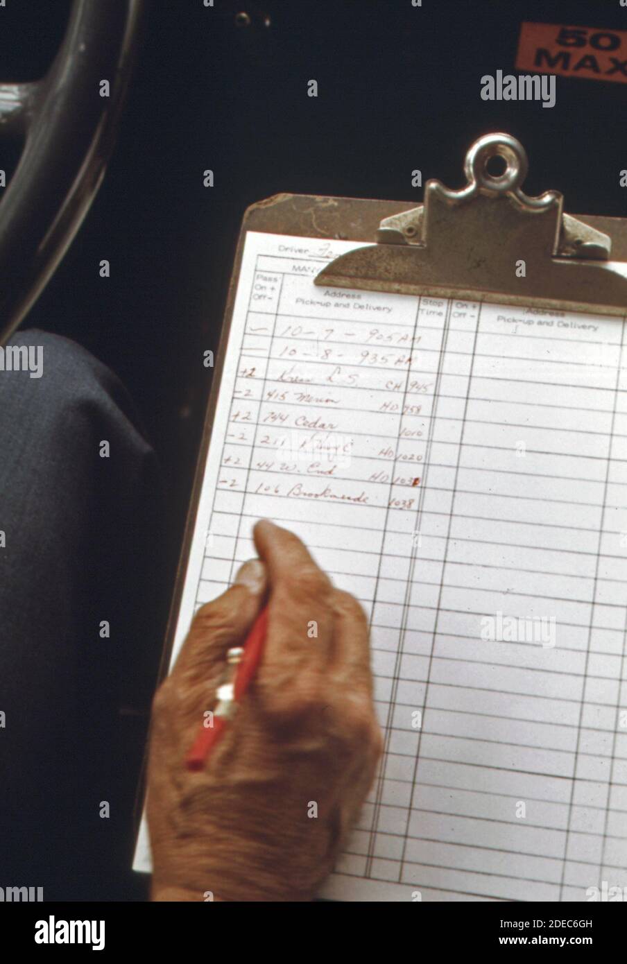 Der Fahrer notiert seine nächste Abholadresse auf einem Dial A Ride Radio, das in Haddonfield einen Tür-zu-Tür-Bus-Service abstellt; New Jersey. Ca. 1974 Stockfoto